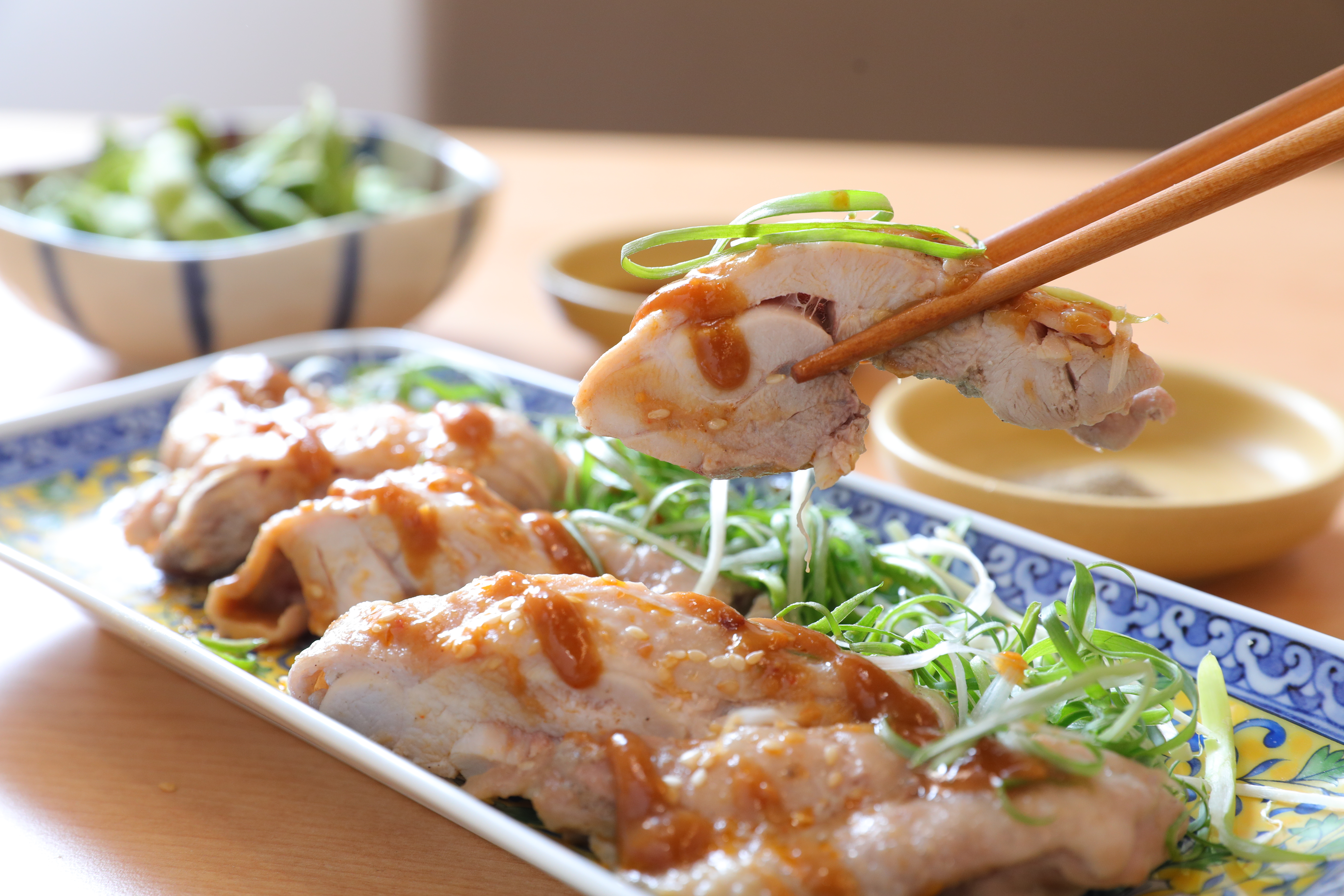 「和風味噌口水雞」是在雞腿肉上澆淋白味噌和豆瓣醬調成的醬汁，配著蔥絲一起入口，甘鹹軟嫩。（220元／份）