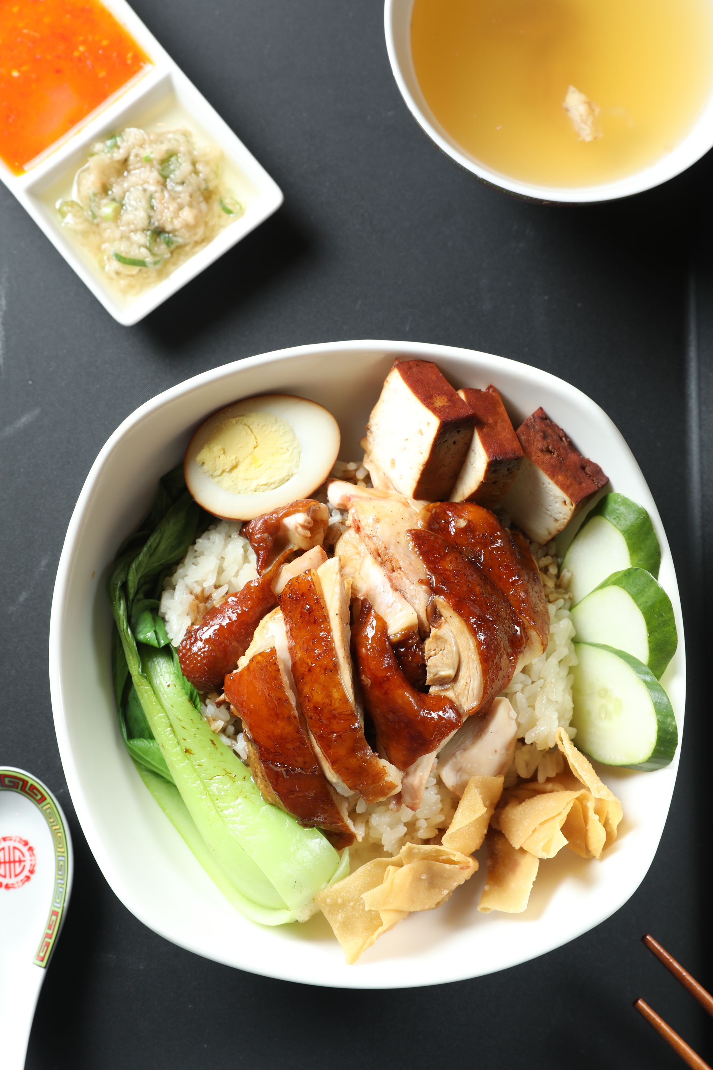 「招牌醬油雞」以泰國香米飯鋪底，擺上青菜、滷豆腐、炸餛飩和滷蛋，雞肉柔嫩入味，雞皮吸附老滷汁的鹹甜香氣。（170元／份）