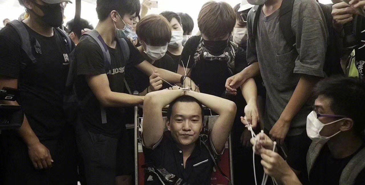 中國《環球時報》記者付國豪被示威者綑綁雙手,綁在手推行李車上。(翻攝自微博)