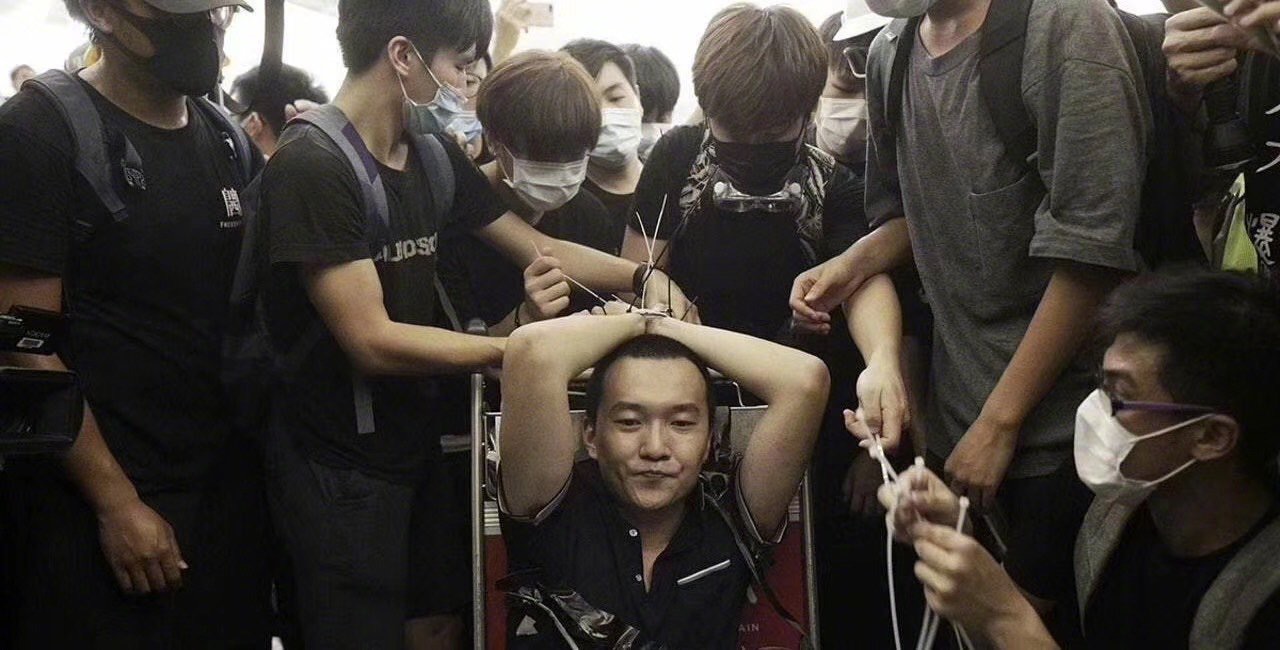 中國《環球時報》記者付國豪被示威者綑綁雙手，綁在手推行李車上。（翻攝自微博）
