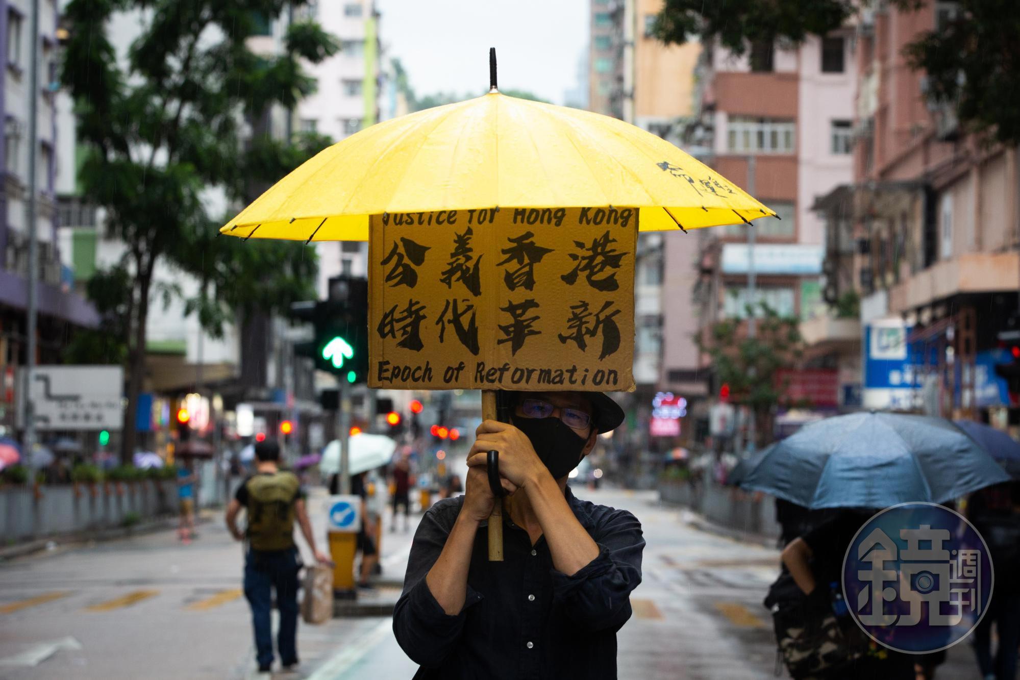 光復紅土遊行下著雷雨，民眾舉著抗議標語。