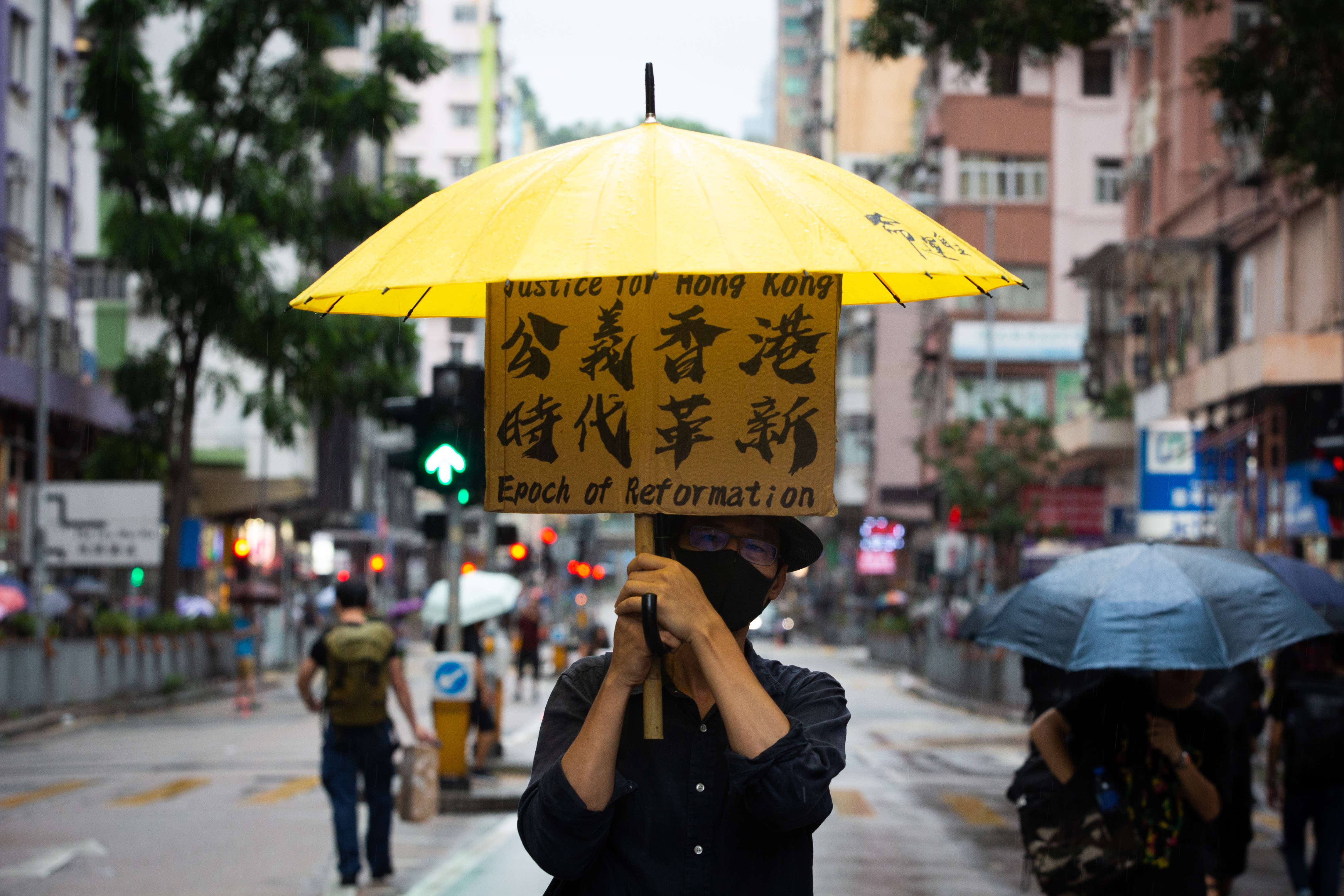光復紅土遊行下著雷雨，民眾舉著抗議標語。