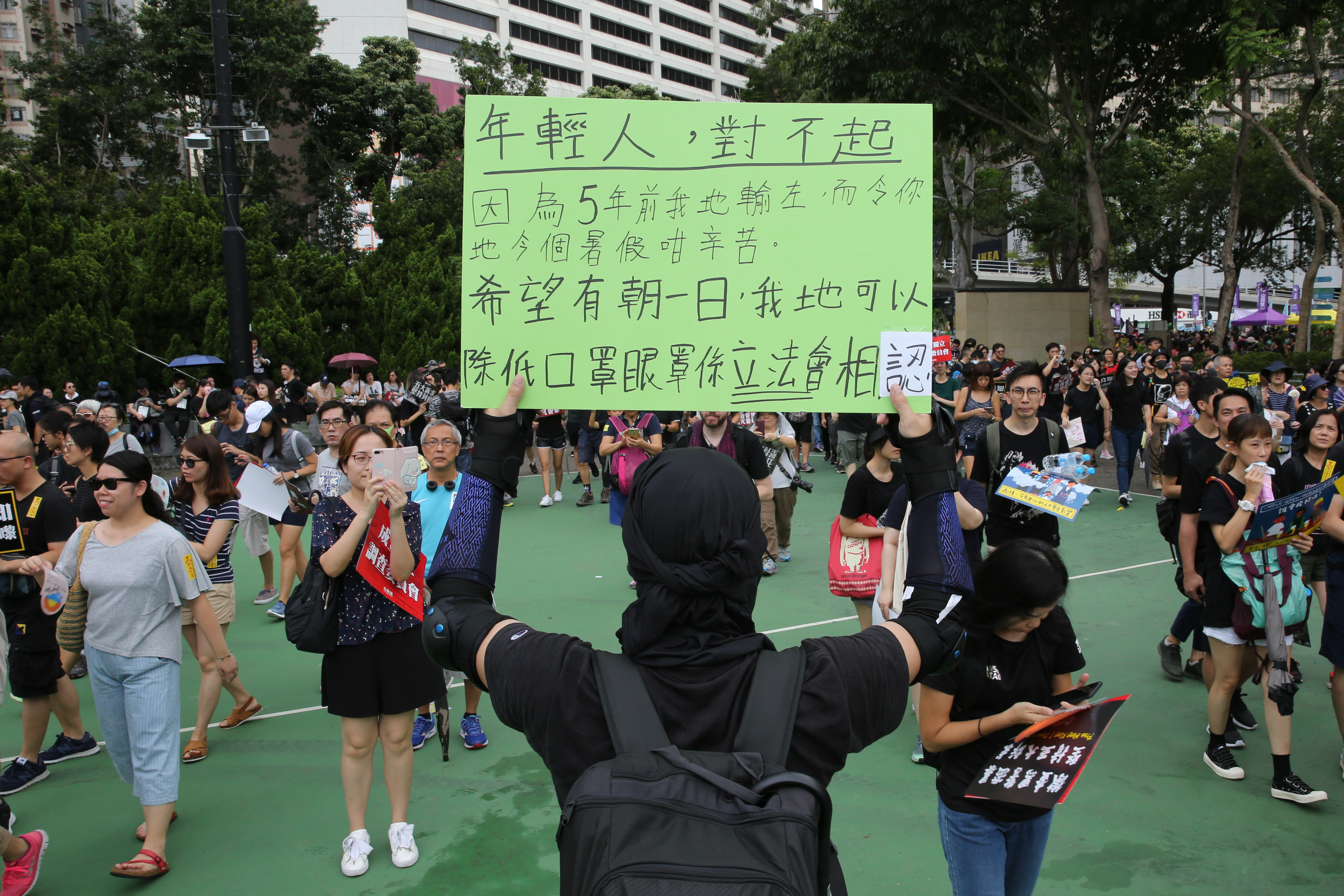 一位勇武派的抗議示威者舉著「年輕人，對不起」的牌子