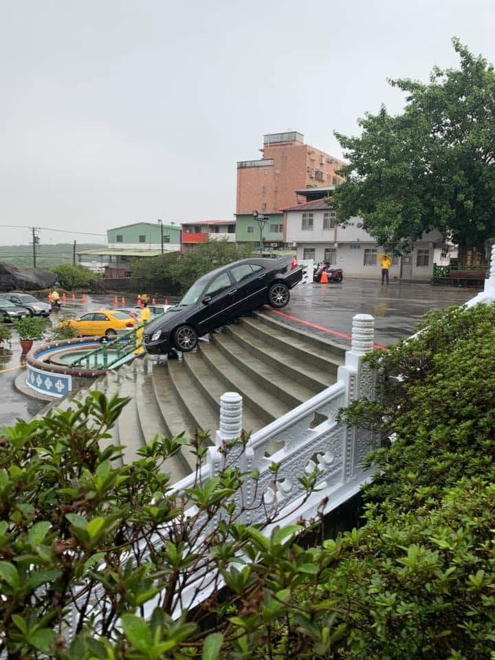 黑色賓士誤踩油門暴衝下台階，卡在淡水天元宮前樓梯動彈不得。（翻攝畫面）
