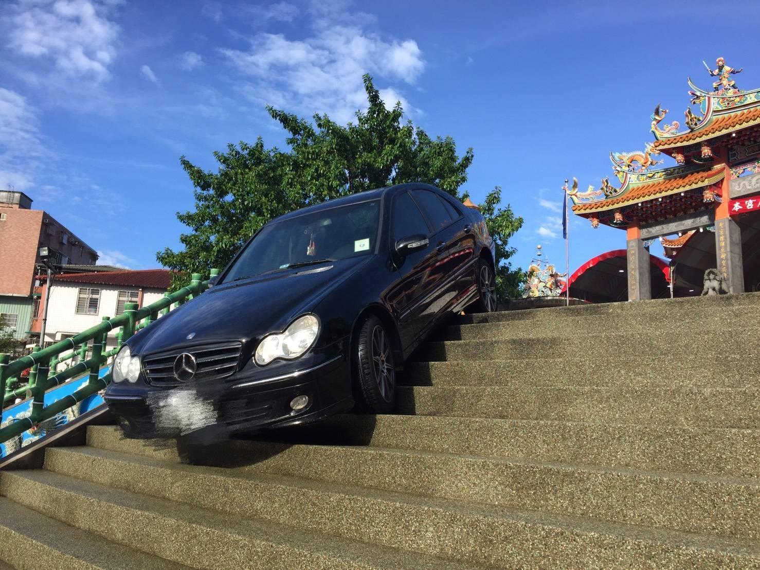 賓士車以詭異90度卡在樓梯上,還好駕駛並未受傷。(翻攝畫面)