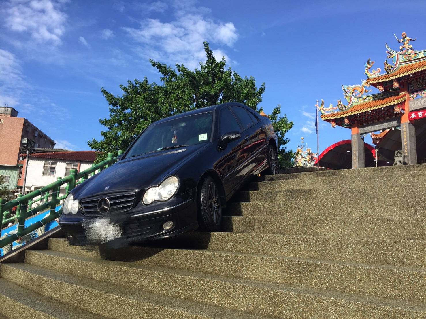 賓士車以詭異90度卡在樓梯上，還好駕駛並未受傷。（翻攝畫面）