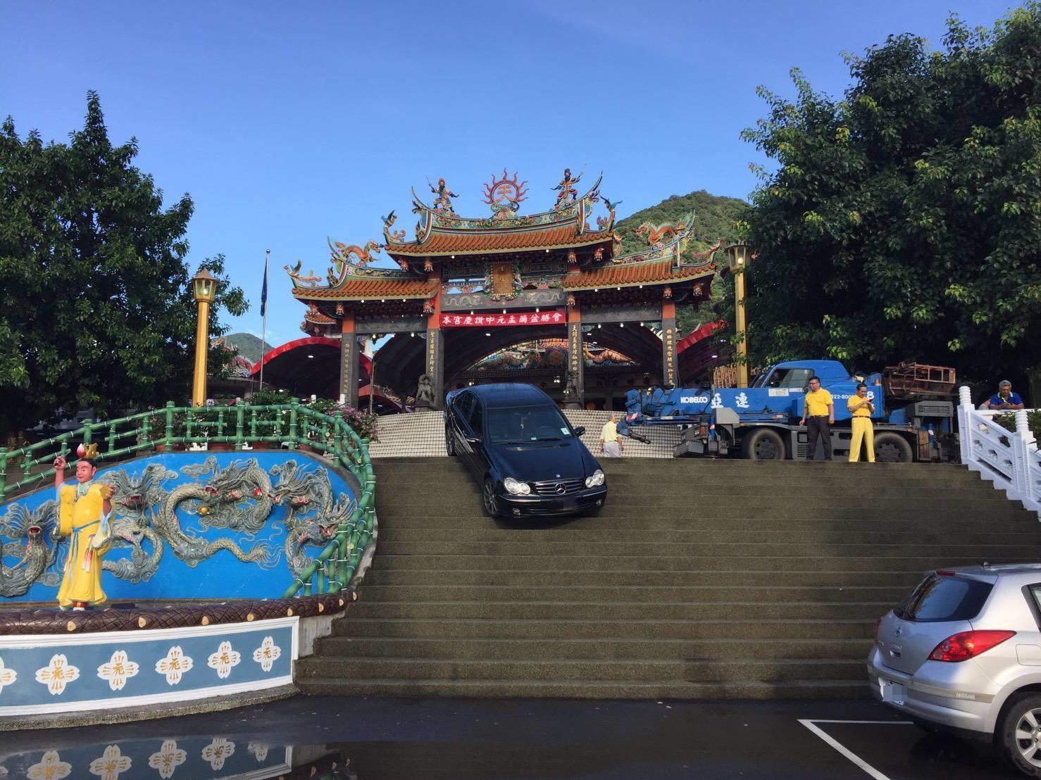 賓士卡在台樓梯上動彈不得,車主無奈找來拖吊車要將車吊起。(翻攝畫面)