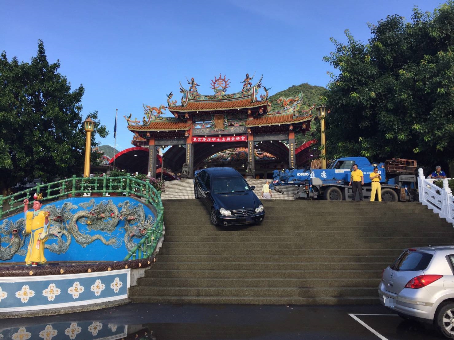 賓士卡在台樓梯上動彈不得，車主無奈找來拖吊車要將車吊起。（翻攝畫面）