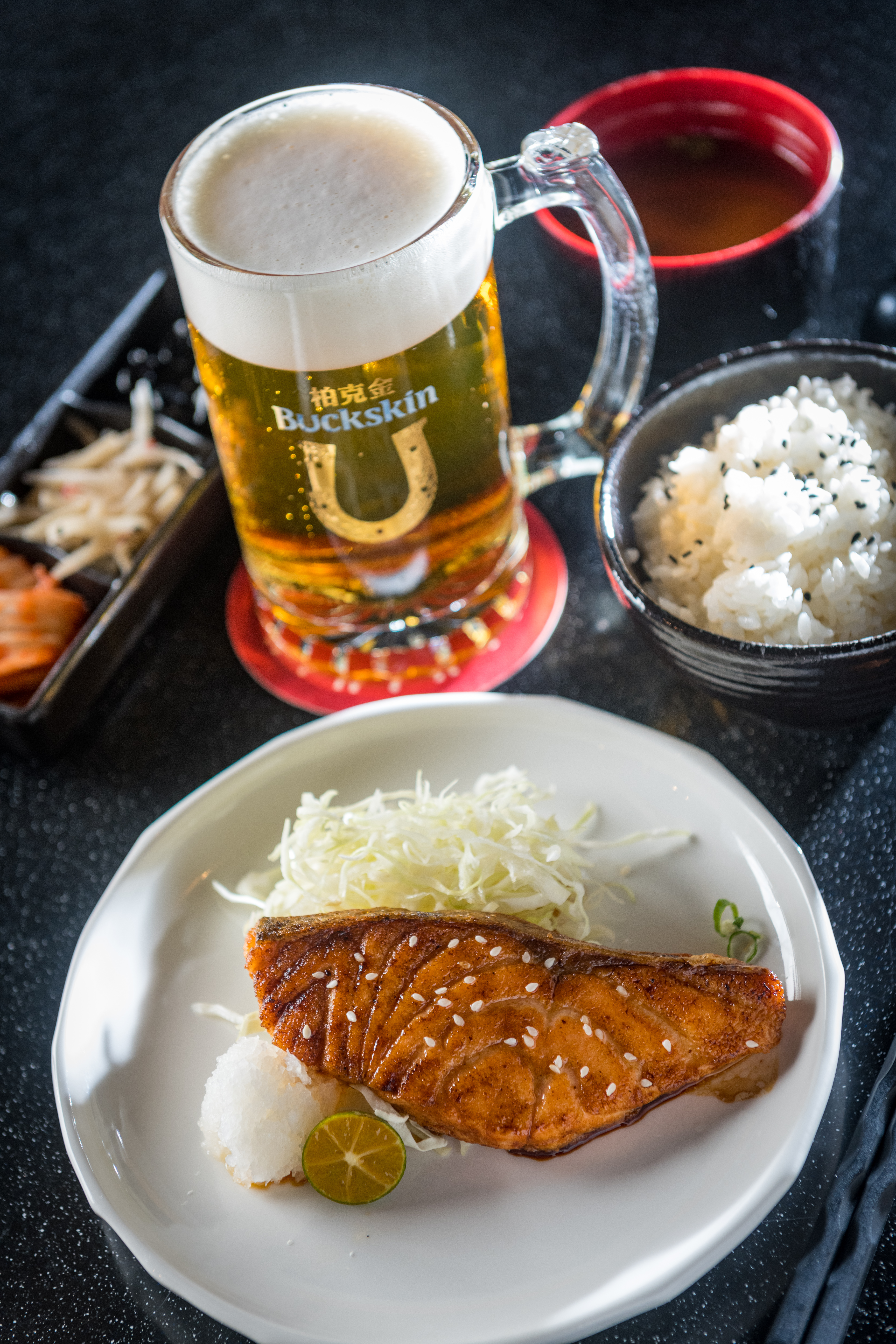 輕盈麥芽風味的「黃金拉格啤酒」(後,260元/500ml)可解「烤鮭魚定食」的豐厚油脂感(前,280元/份,商業午餐)