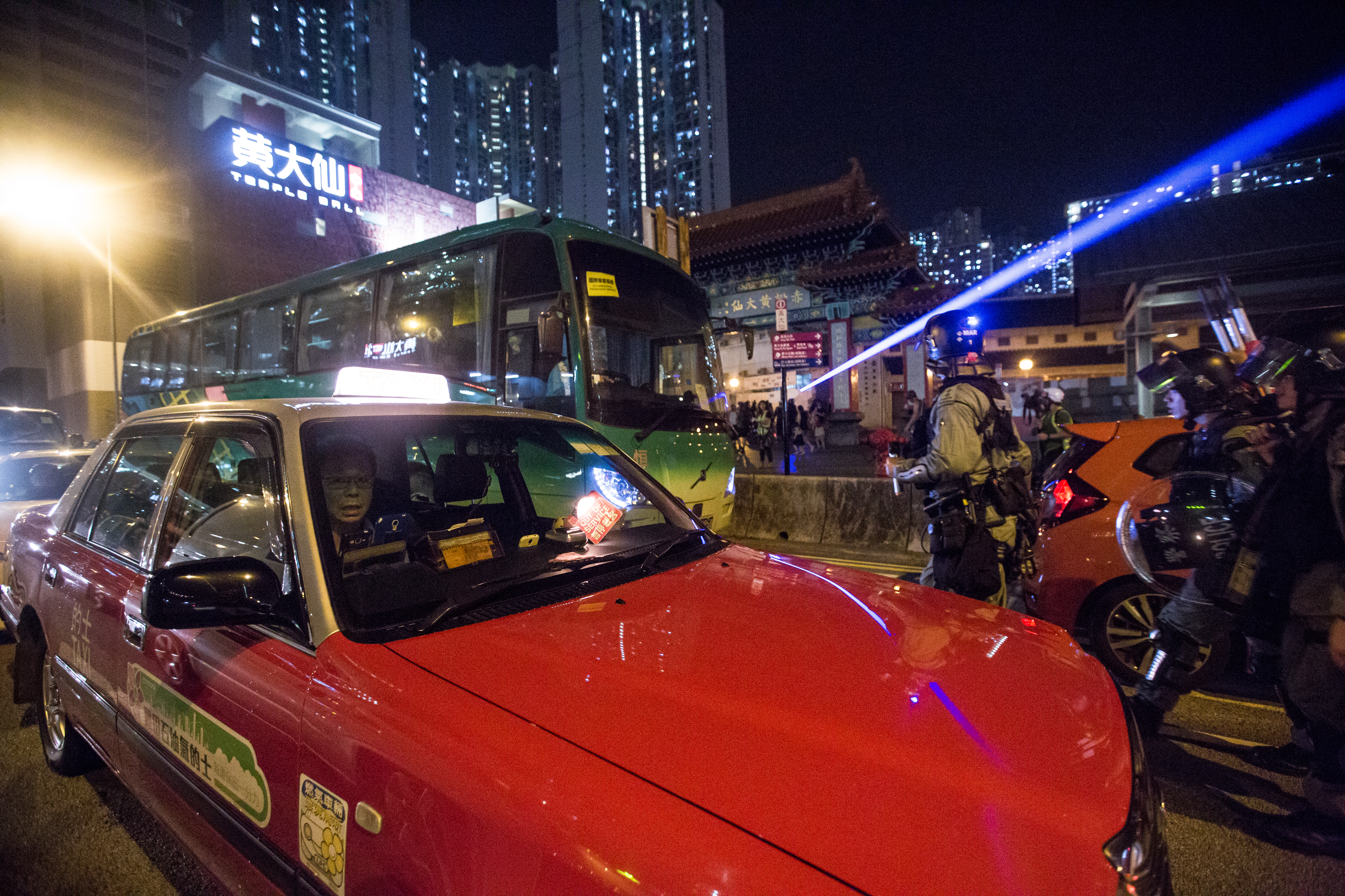 警方於黃大仙龍翔道上的車陣中追逐逼退示威者。