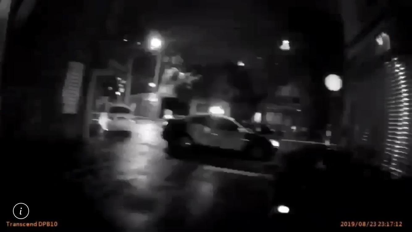 疑似擄人的白色轎車從巷弄內竄出，企圖衝中執勤員警，遭警開一槍後逃逸。（翻攝畫面）