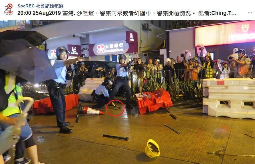 香港昨(25)日發起「荃葵青大遊行」,有網友發現港警疑似為了撿掉槍(紅圈處),而拔槍威嚇市民。(翻攝自SocREC 社會記錄頻道臉書)