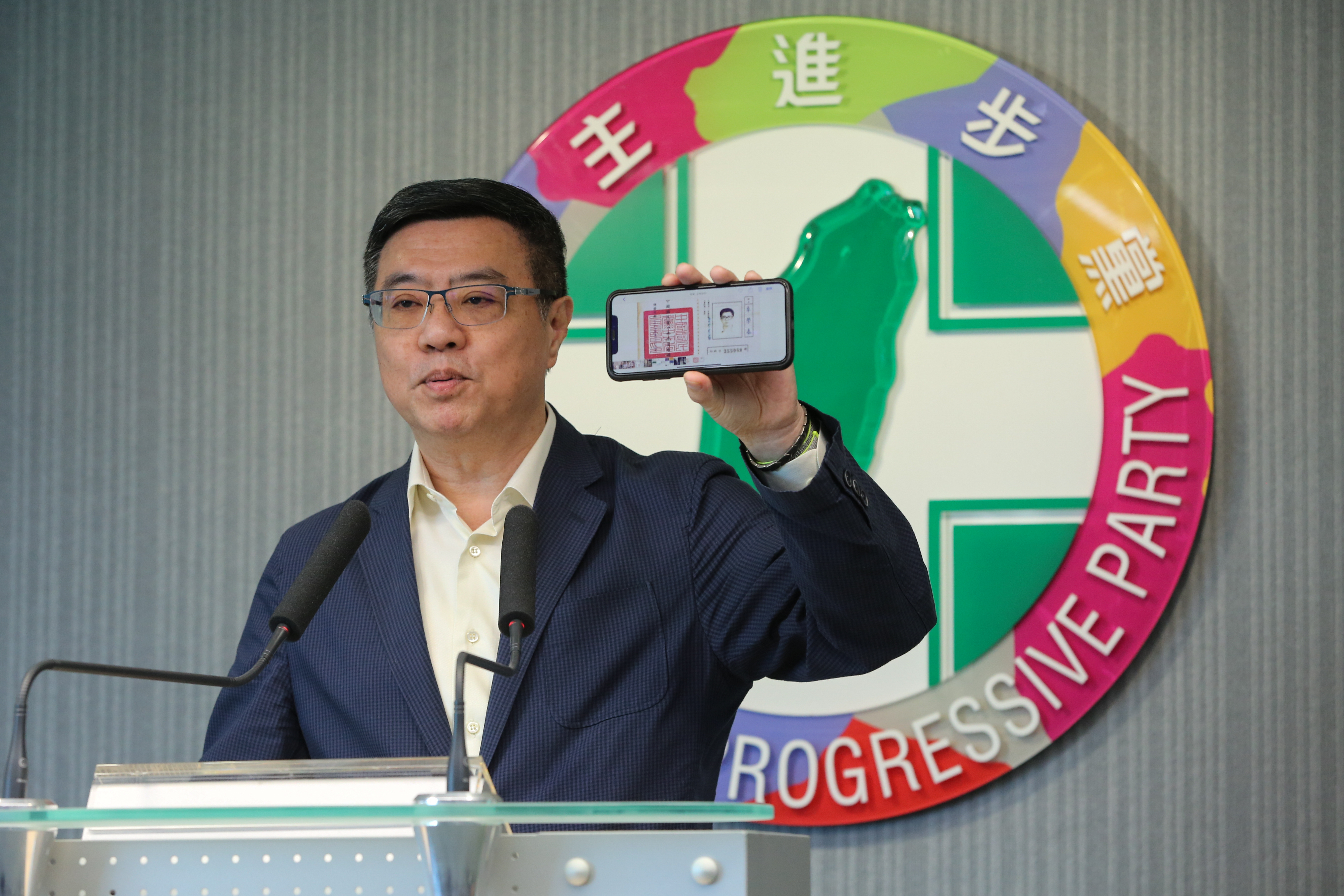 民進黨主席卓榮泰在記者會上秀出40年前他的國民黨證。