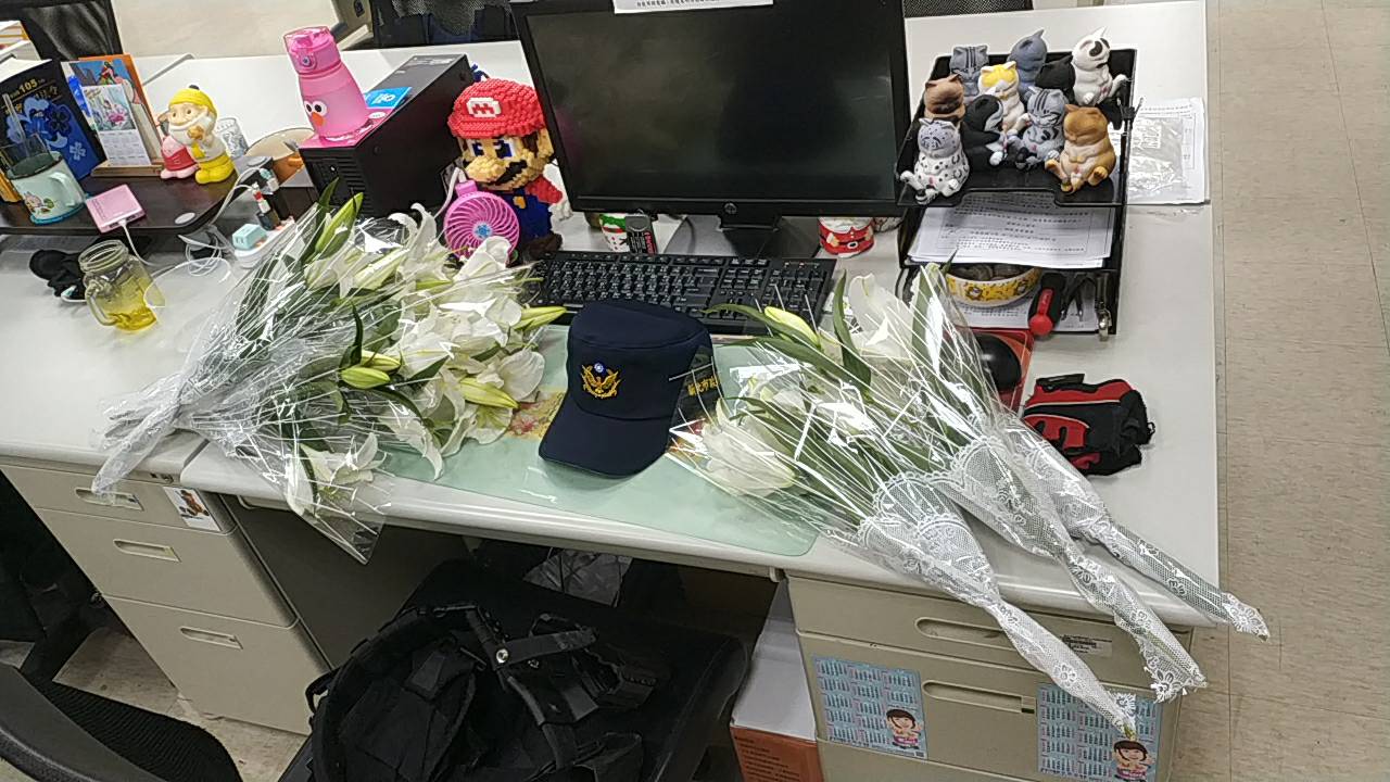 汐止派出所員警薛定岳追緝毒蟲不幸殉職，所內其座位堆放著各界送來的悼念花束。（翻攝畫面）