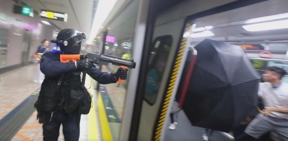 香港警方朝著車廂內對著乘客施放胡椒噴霧，乘客撐開雨傘抵擋。（翻攝梁柏堅臉書粉絲專頁影片）