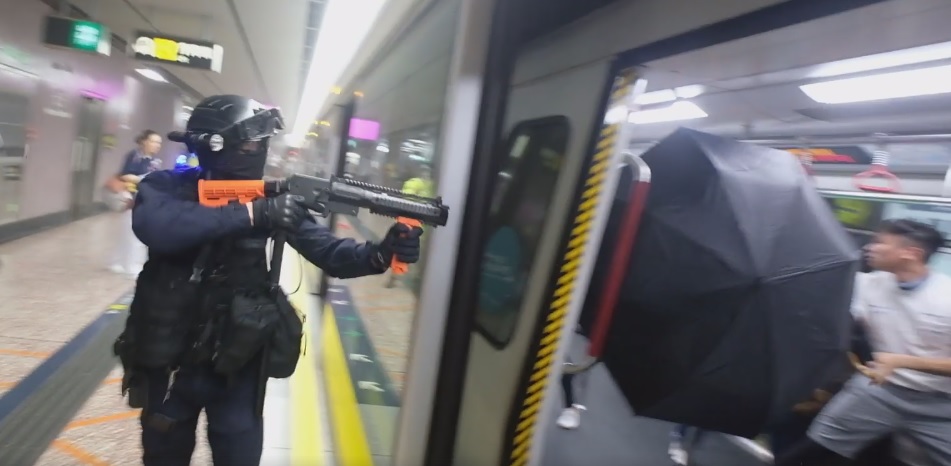 香港警方朝著車廂內對著乘客施放胡椒噴霧，乘客撐開雨傘抵擋。（翻攝梁柏堅臉書粉絲專頁影片）