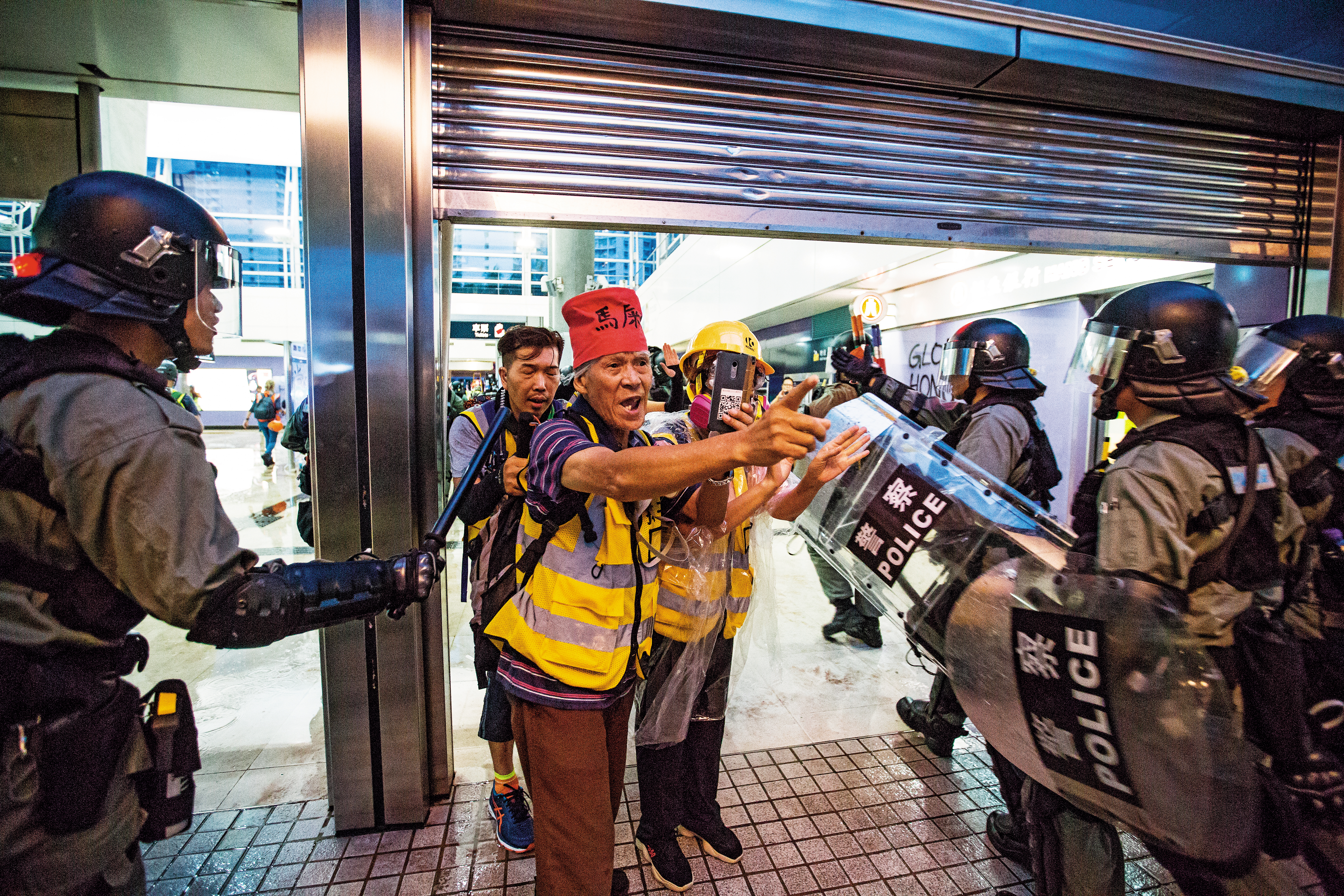 身著「守護孩子」背心的陳伯（戴紅帽者）一直站在示威者與警察之間。