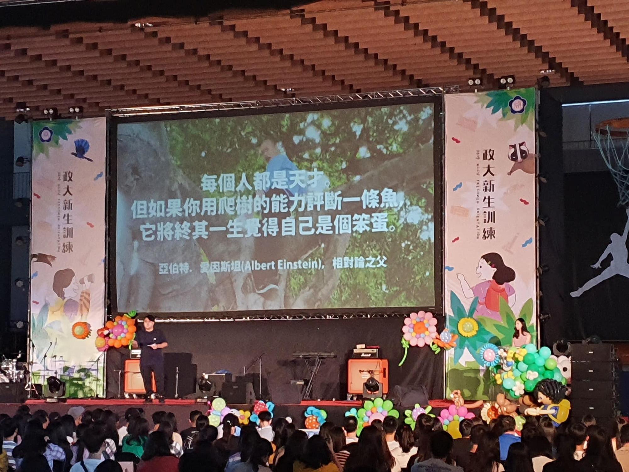 政治大學昨(4日)舉辦108學年度新生訓練,學生會長致詞時竟出現「韓國瑜爬樹」照,引起熱議。(翻攝自行走的故事詩/yanwu臉書)