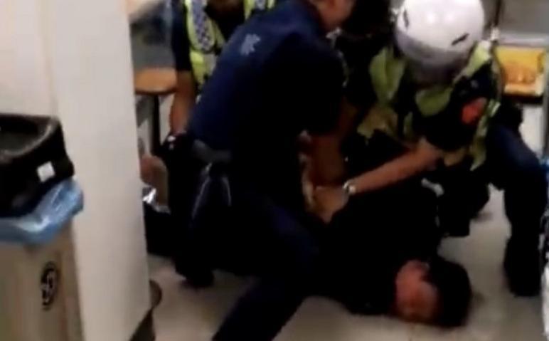 員警聯手將男子壓制在地帶回保護管束。（讀者提供）