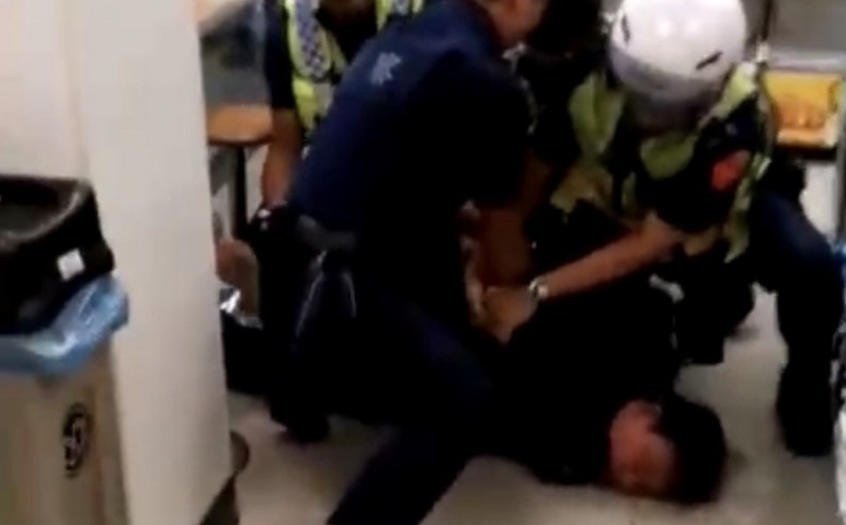 員警聯手將男子壓制在地帶回保護管束。（讀者提供）