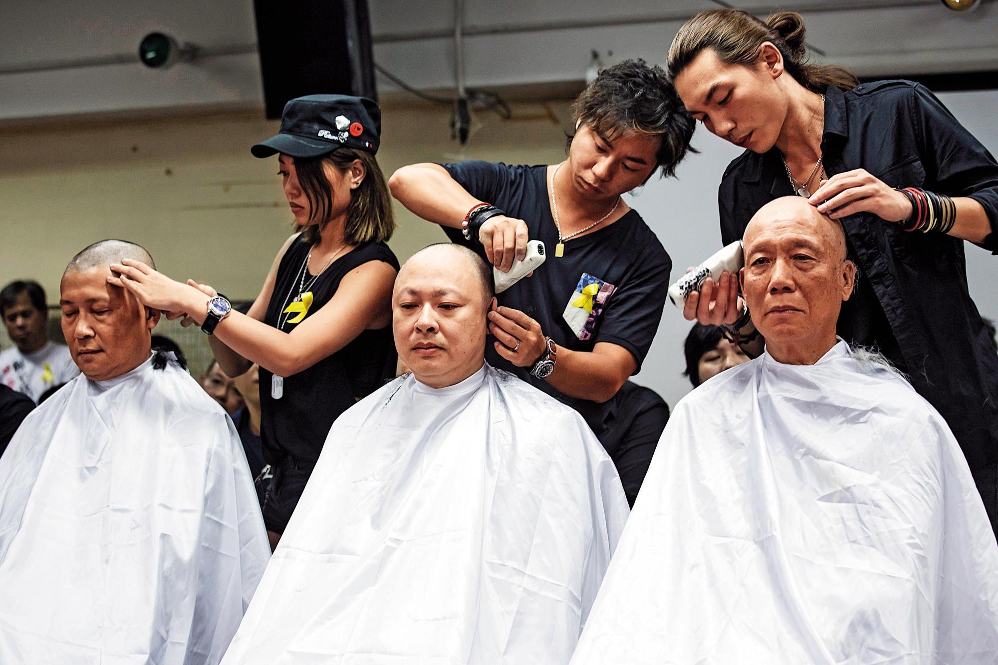 2014年9月,「占中三子」戴耀廷(中)、朱耀明(右)和陳健民(左)帶領一批民眾剃光頭,表達公民抗命、爭取真普選的決心。(達志影像)