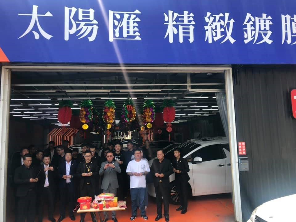 謝育全（中間身著灰色西裝）位於苗栗的車行，直接以太陽匯為名，絲毫不忌諱別人的眼光。（翻攝自連千毅臉書）