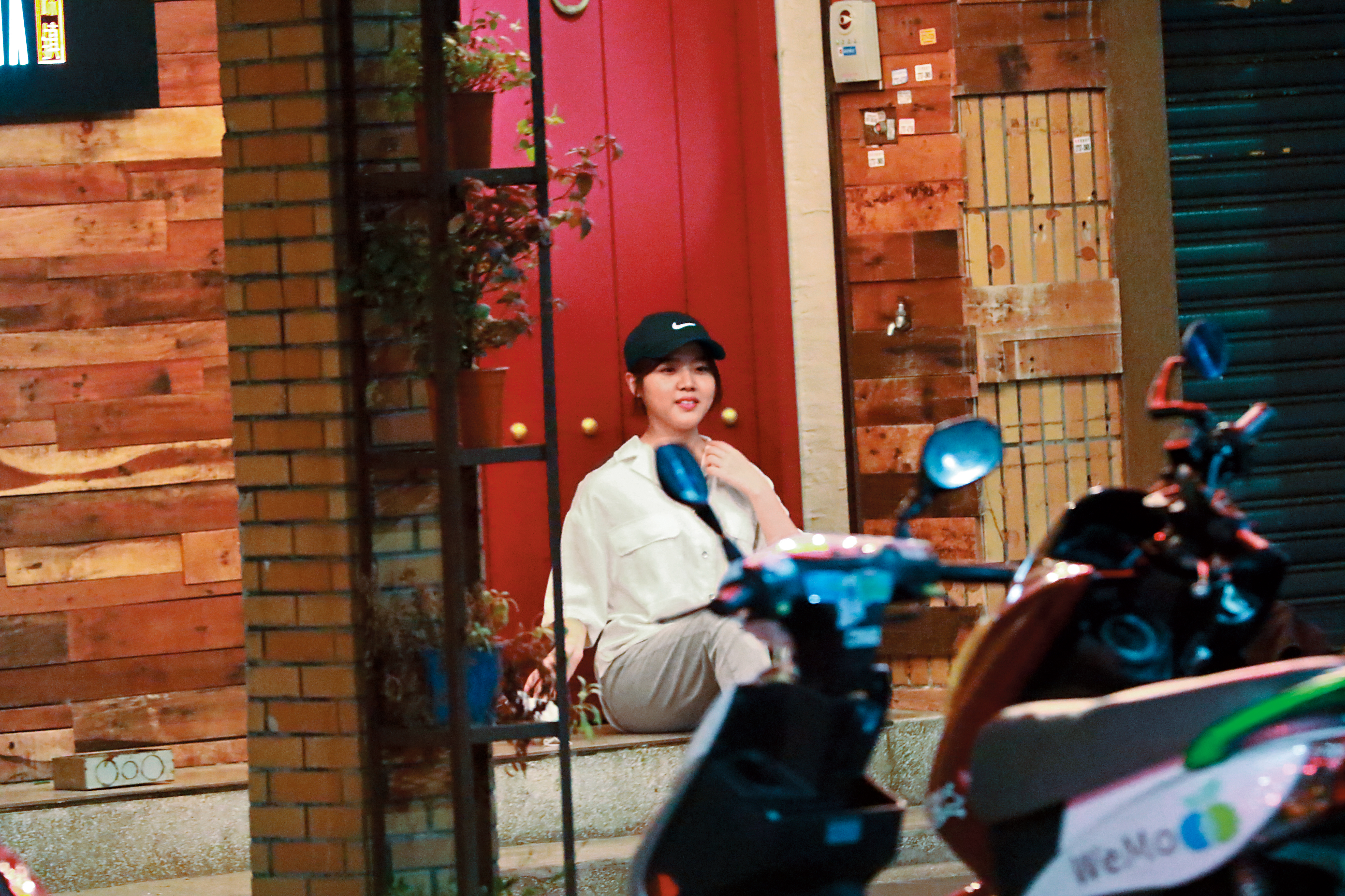 9/22 22:49 金香起脫下帽子和口罩坐在酒吧門口，請工作人員為她拍照留下在台灣的紀念照。