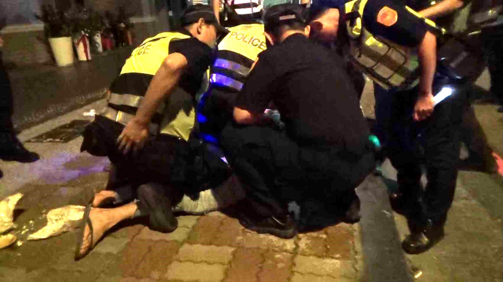 男子凌晨到連千毅公司前砸漢堡叫囂，被警方壓制逮捕。（翻攝畫面）