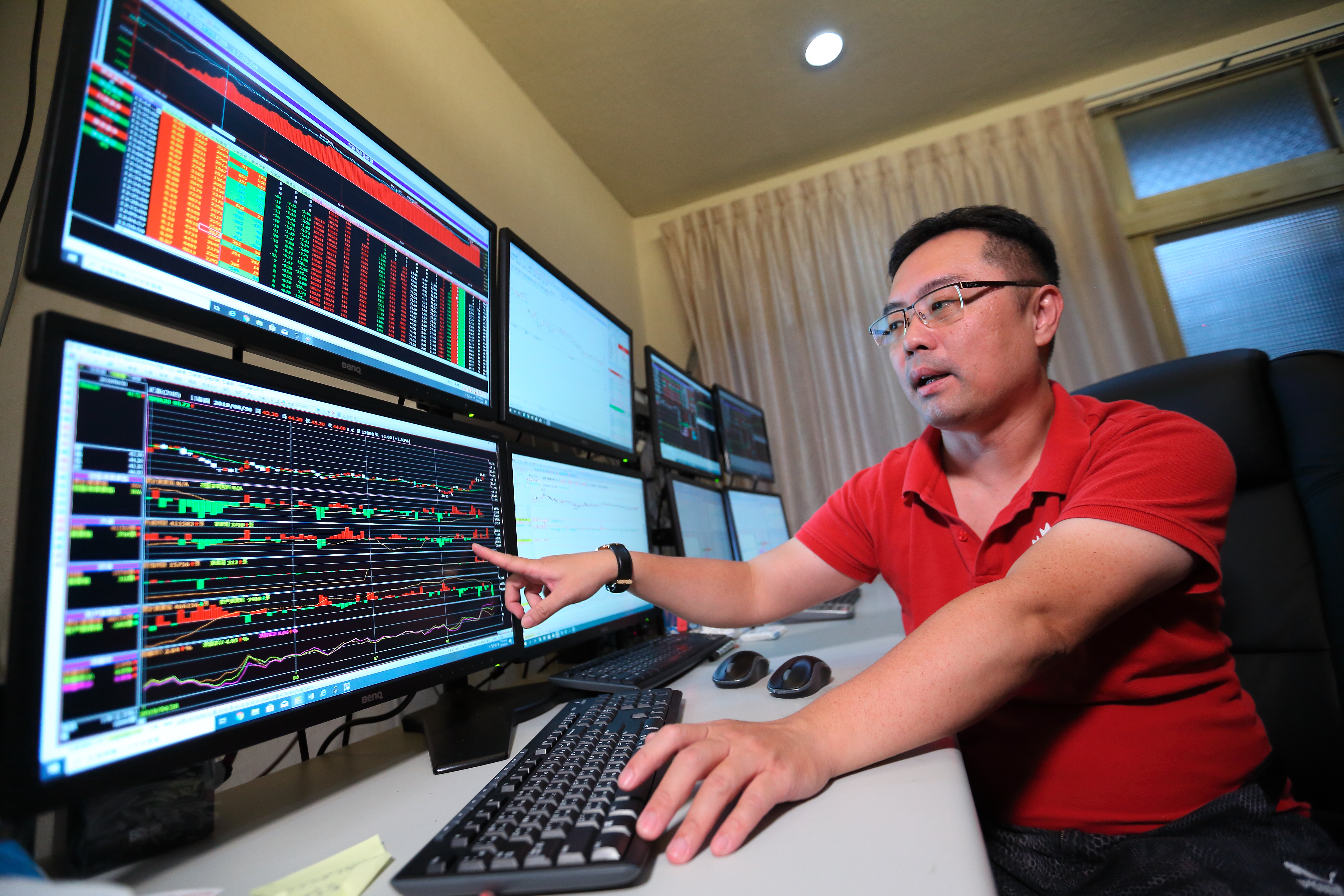 看盤室中8台螢幕一字排開，戴成霖天天關注股價變動，每年從股市中提款百萬。