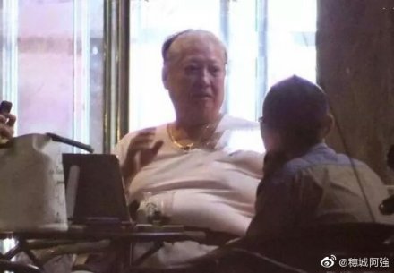 洪金寶被拍到坐輪椅抽雪茄，頂上毛髮稀疏花白，脂肪堆積成多層肥肉塔。（翻攝自穗城阿強微博）