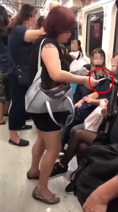 黑衣女子從包包掏出粉紅色小卡,要求坐在博愛座上的金髮女子讓座。(翻攝自爆料公社)