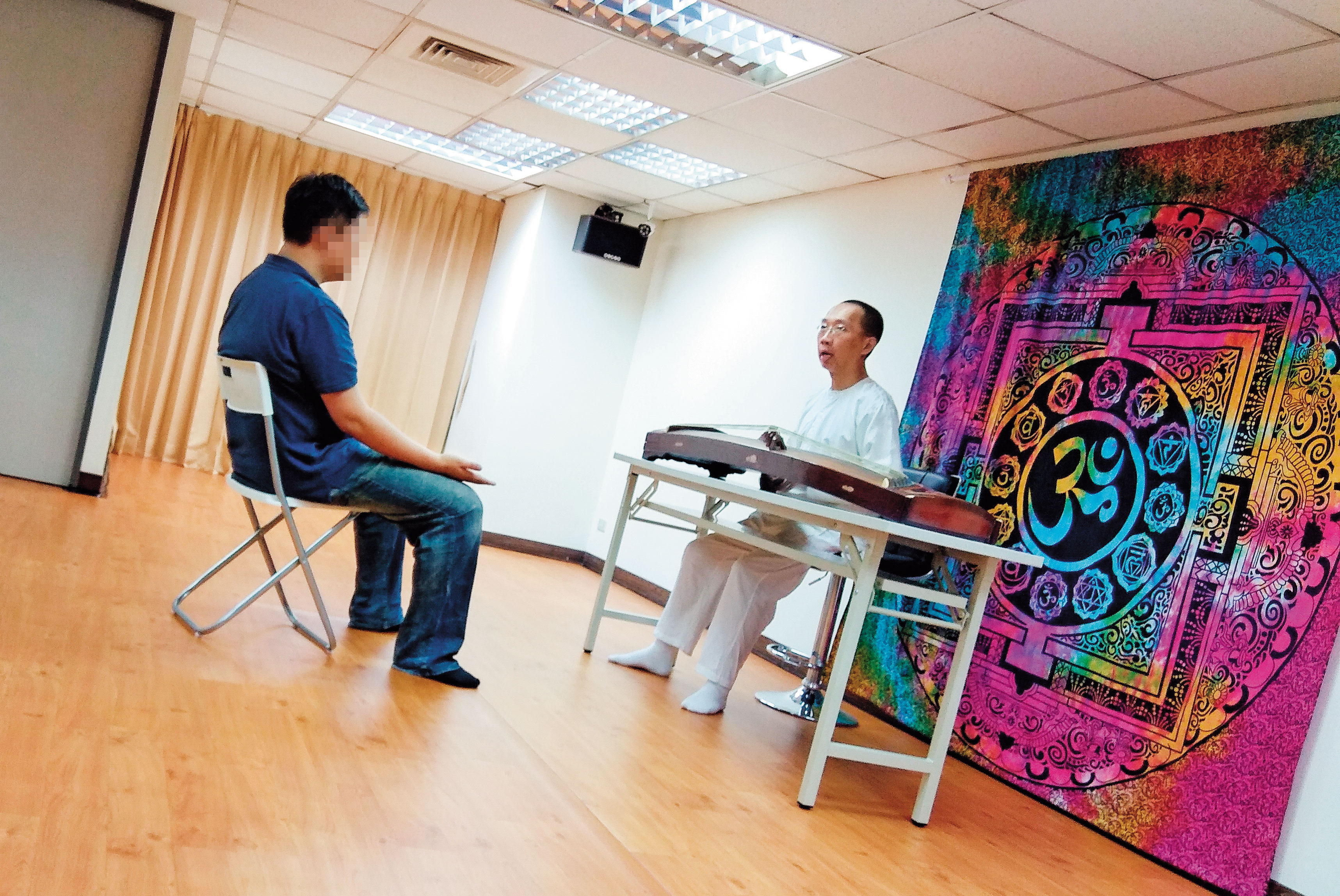 許台融（右）要記者坐在古箏前，宣稱能藉彈奏古箏傳輸能量，治療記者身上疾病。