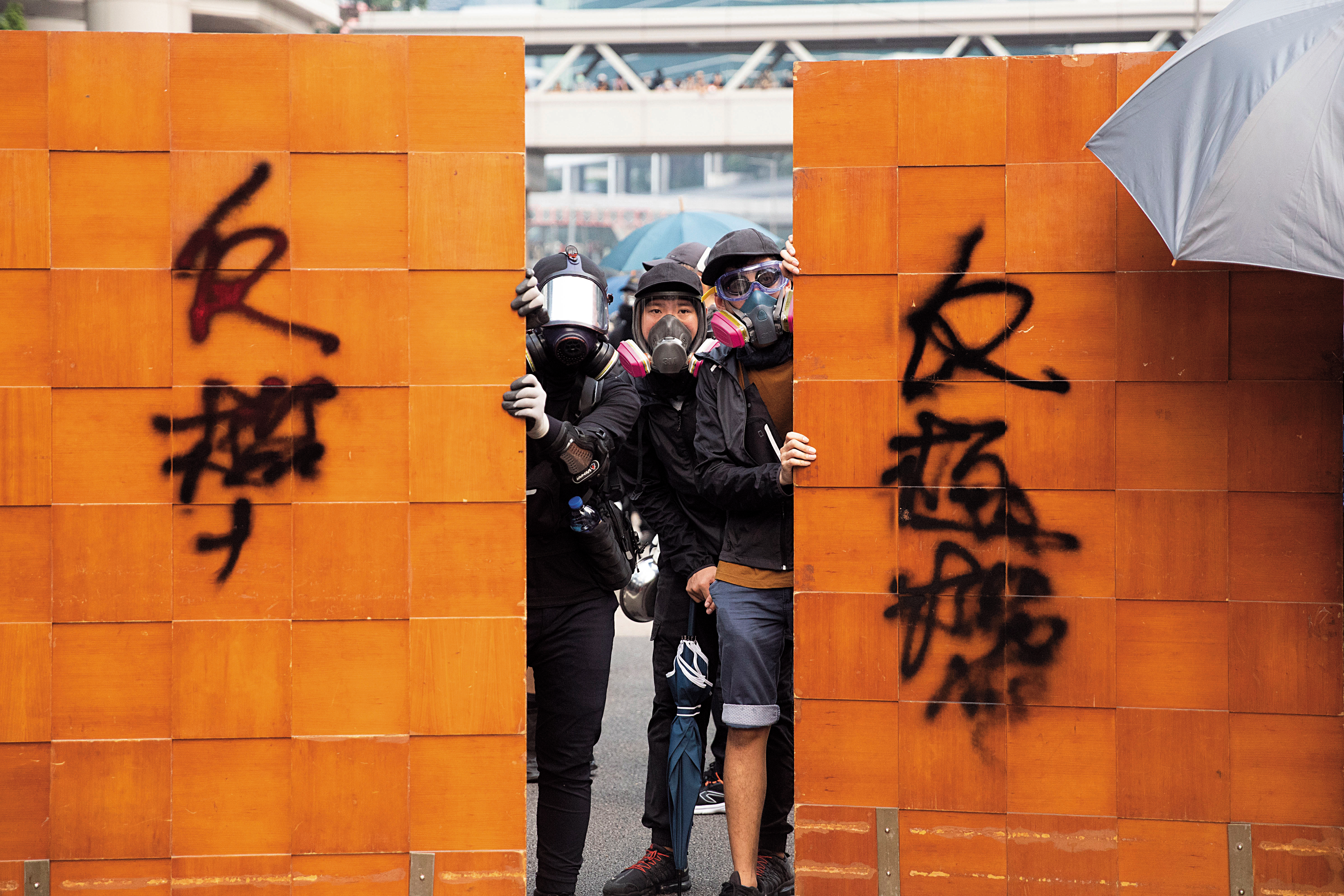 示威者就地取材拿起木板抵擋催淚瓦斯。