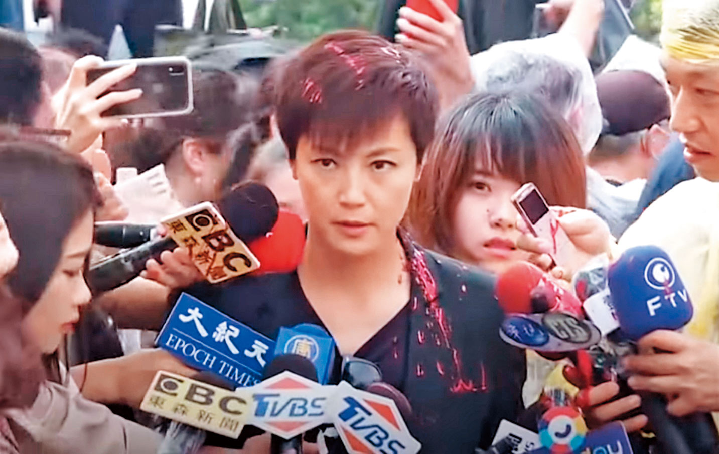 香港歌手何韻詩，在接受媒體訪問時，突然被戴臉罩的兩位男性嫌犯，從背後潑灑紅漆攻擊。（翻攝自新唐人電視台）