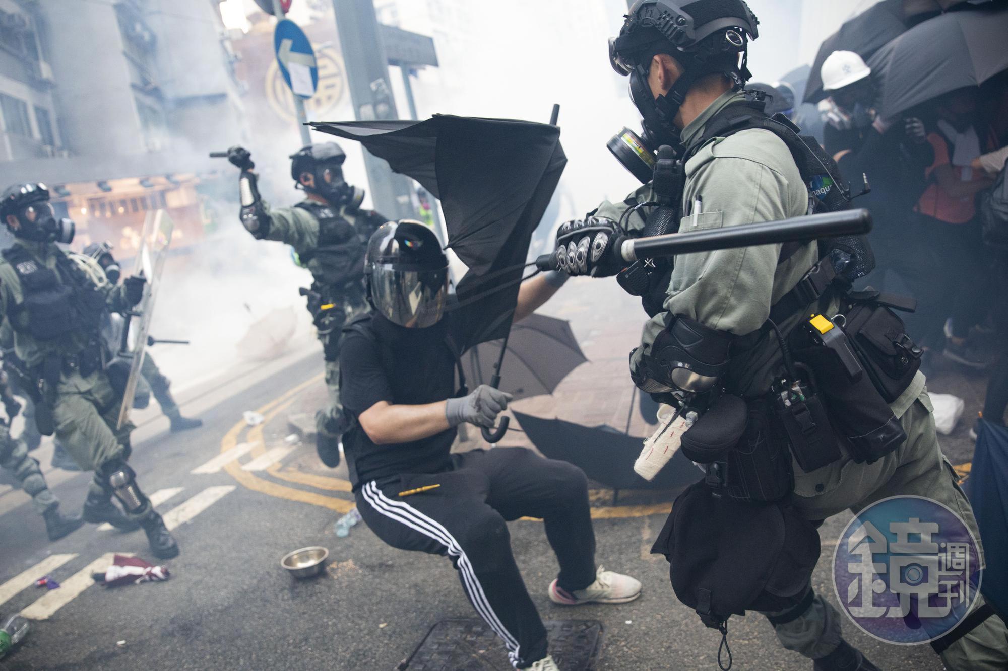 一名抗爭者在灣仔街頭以雨傘抵抗警長的棍棒槍砲。
