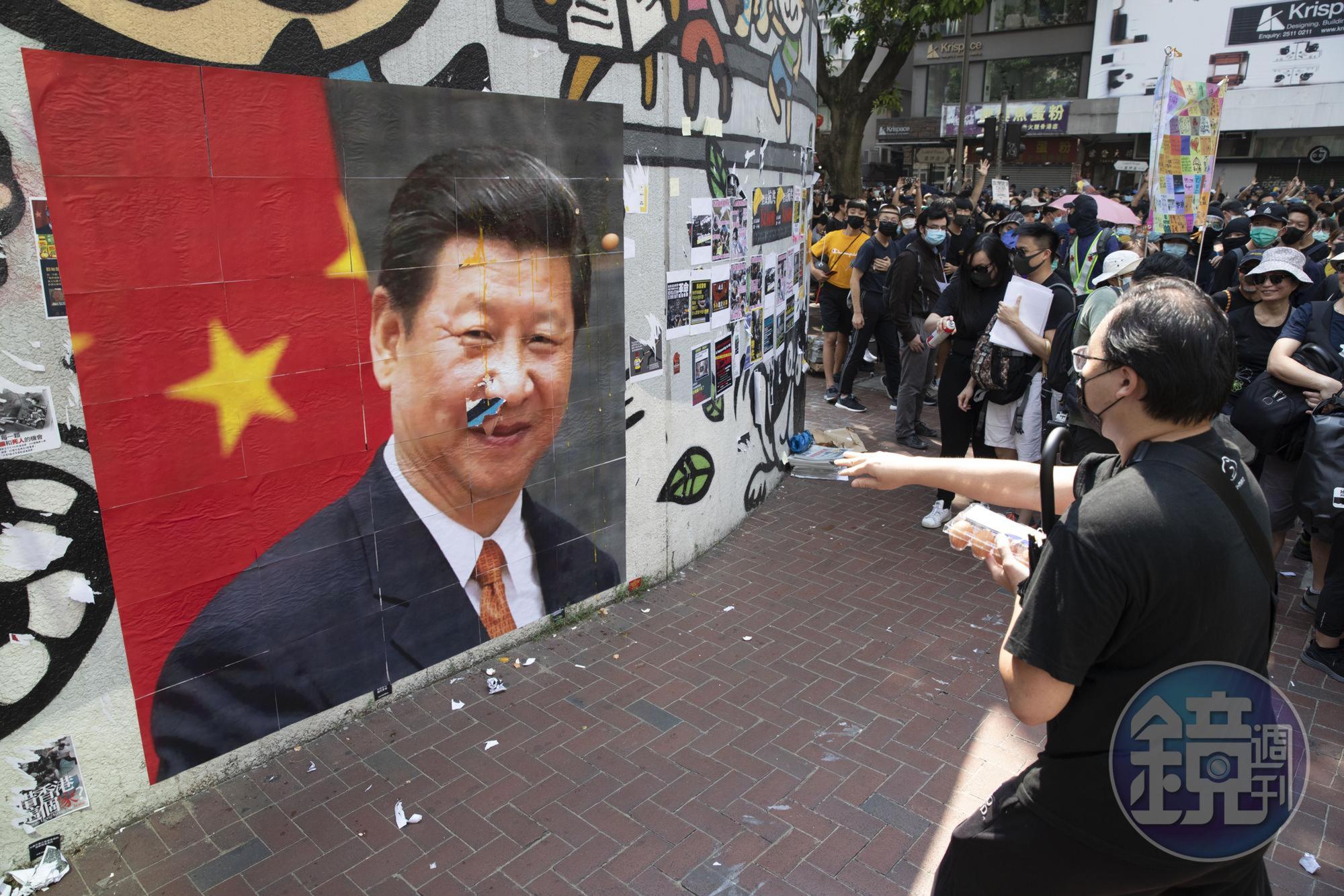 民眾在灣仔人行道外牆張貼習近平照片,並輪流丟擲雞蛋。