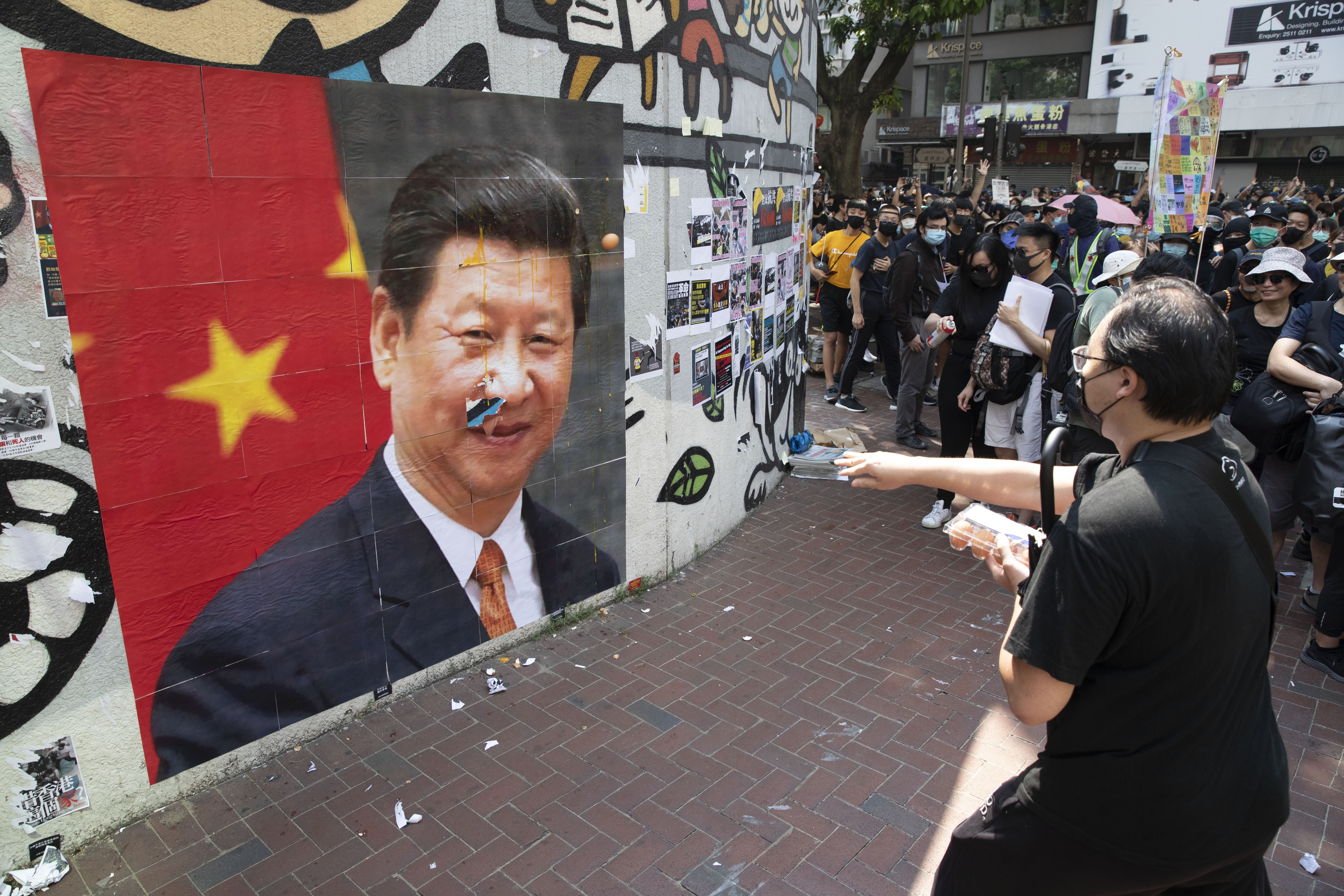民眾在灣仔人行道外牆張貼習近平照片,並輪流丟擲雞蛋。