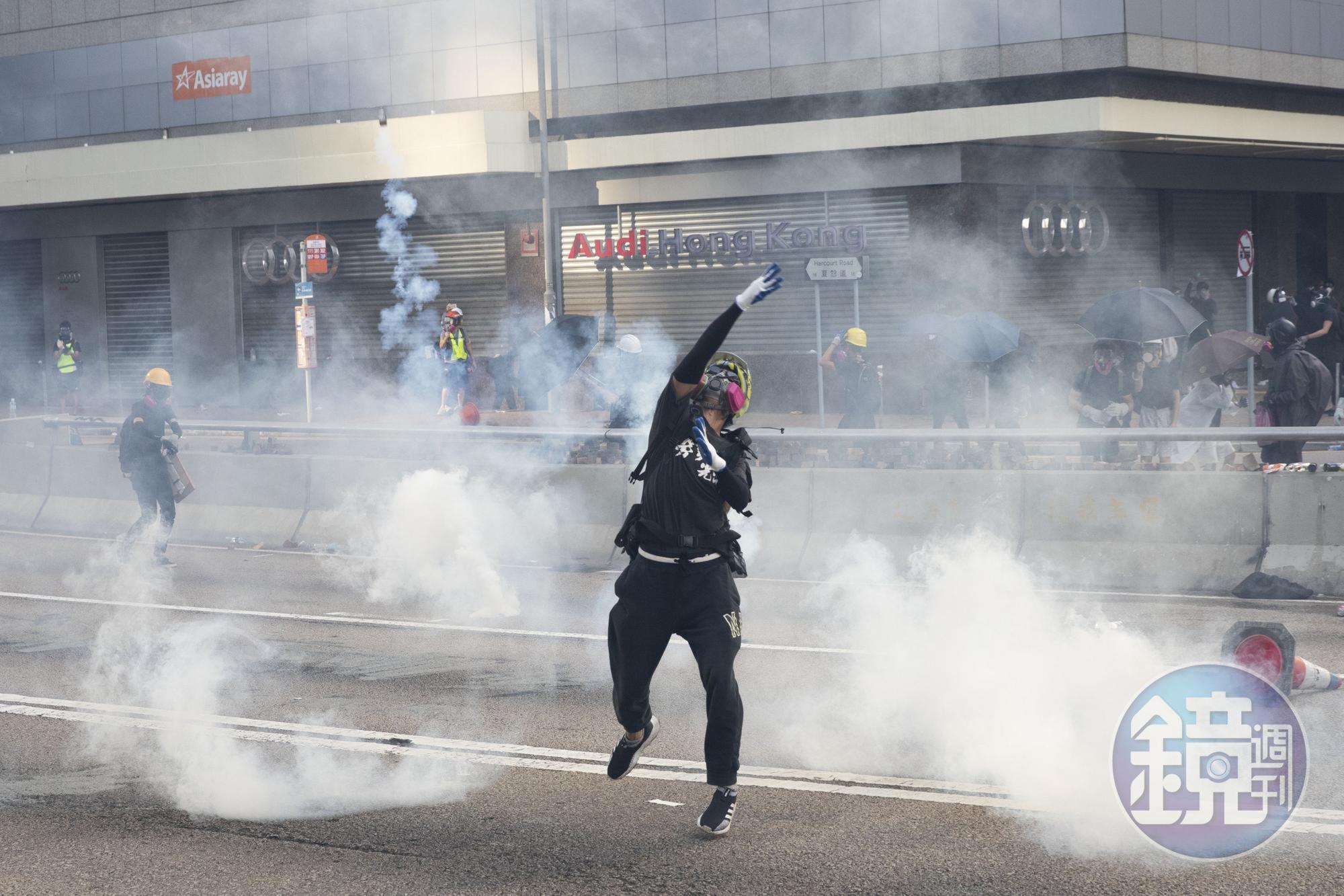 前線一名勇武派抗爭者拾起一枚防爆彈回擲警方。