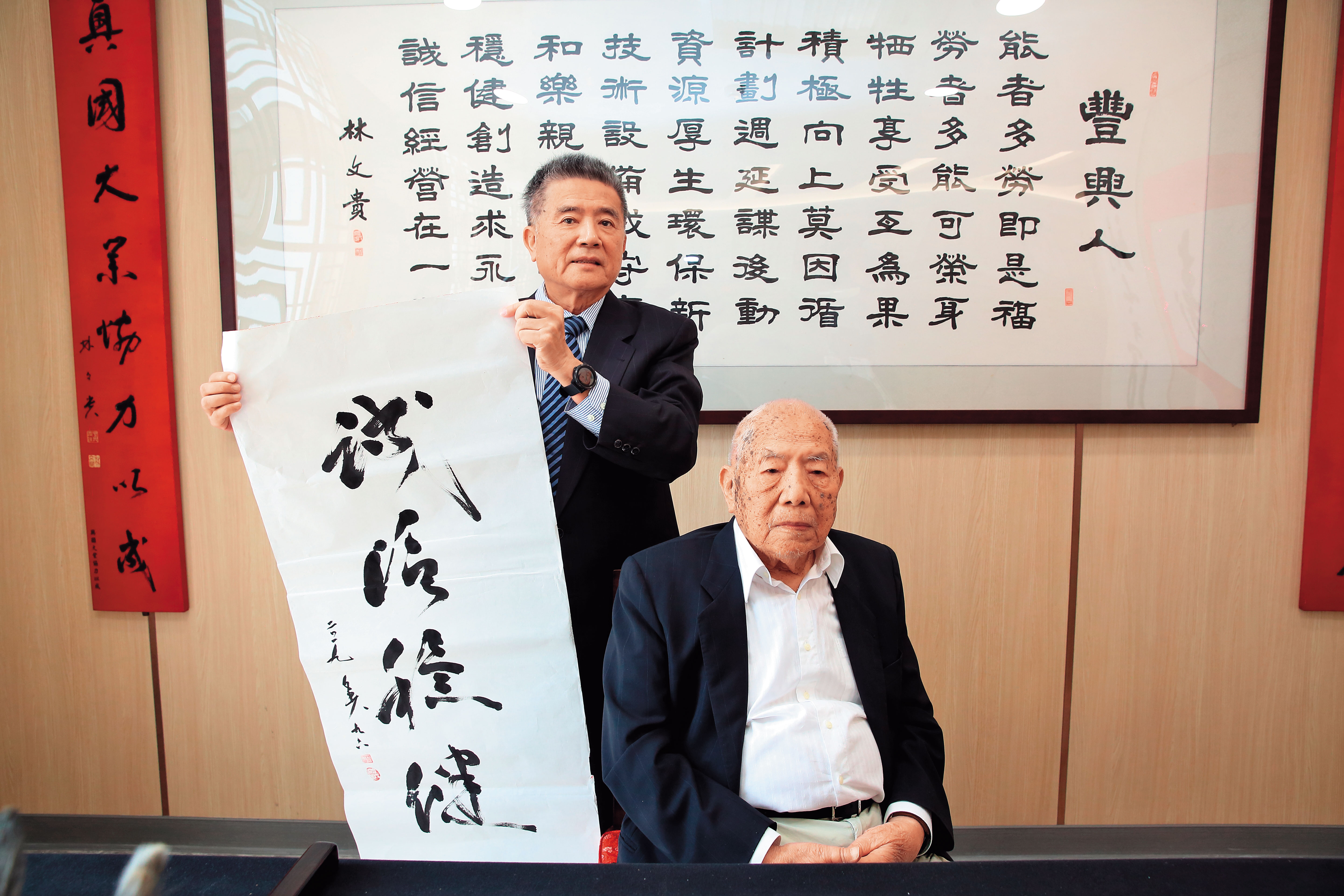 林文貴(右)在紙上寫下「誠信穩健」,提醒下一代經營公司不能投機取巧。