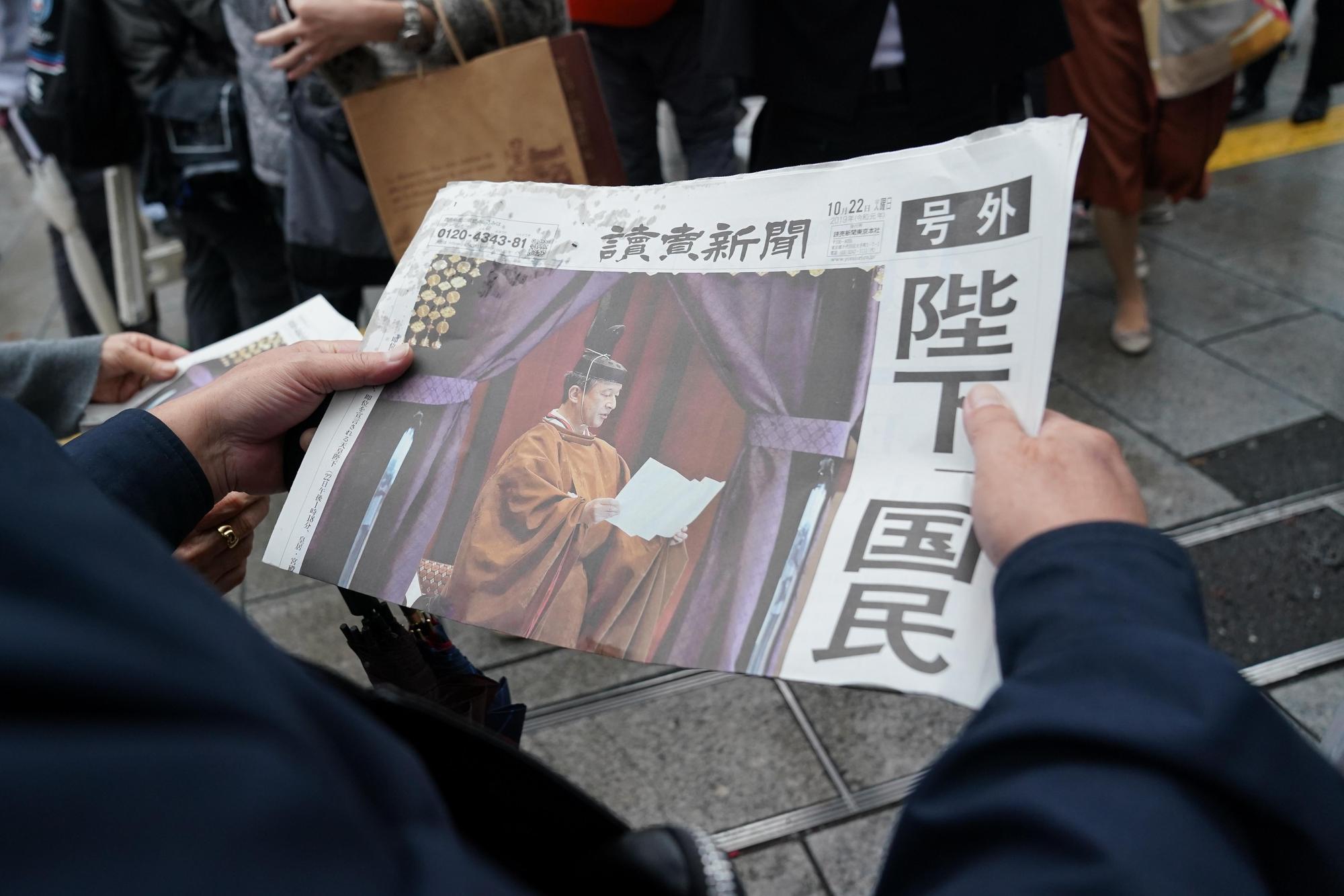 2019年10月22日，日本東京街頭發送關於天皇登基儀式的報紙號外（達志影像）