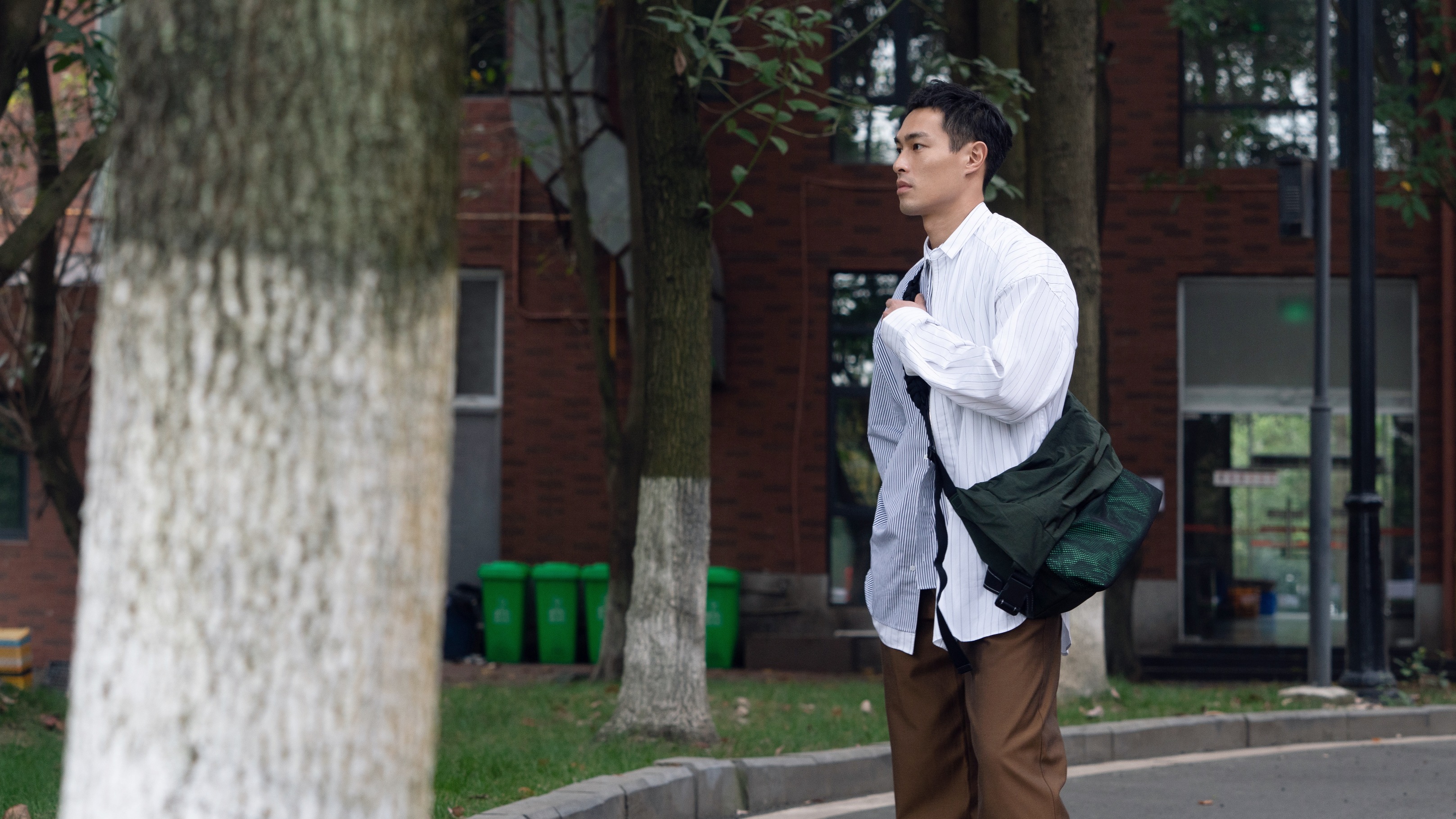 楊祐寧以oversize的條紋襯衫搭配寬版休閒褲與黑色休閒鞋，背起BOTTEGA VENETA的新款包潮味十足。 BOTTEGA VENETA紙感尼龍斜背包 NT$54,100（BOTTEGA VENETA提供）