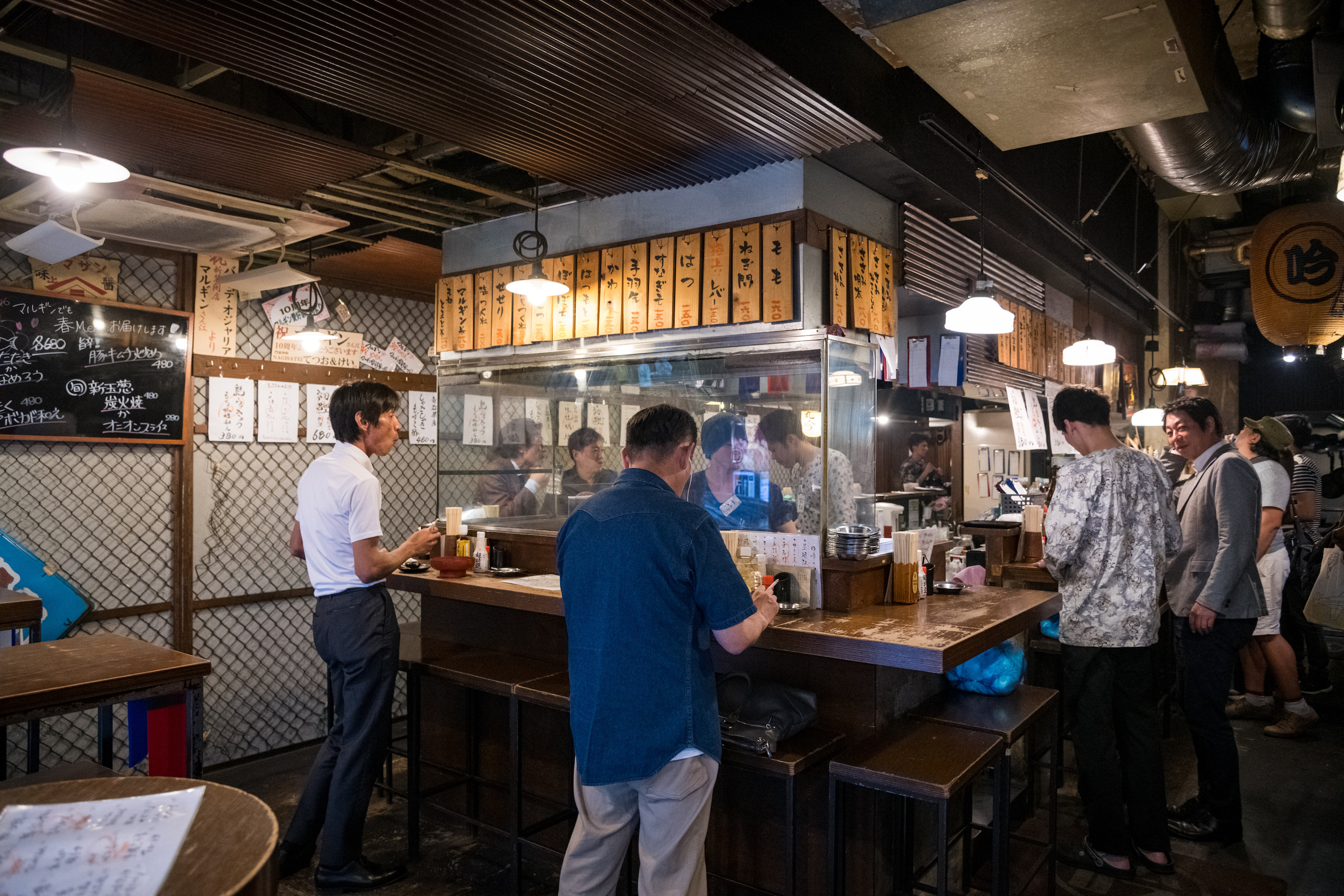 在「丸吟」，大家圍繞著中央烤台立食，氣氛熱烈。