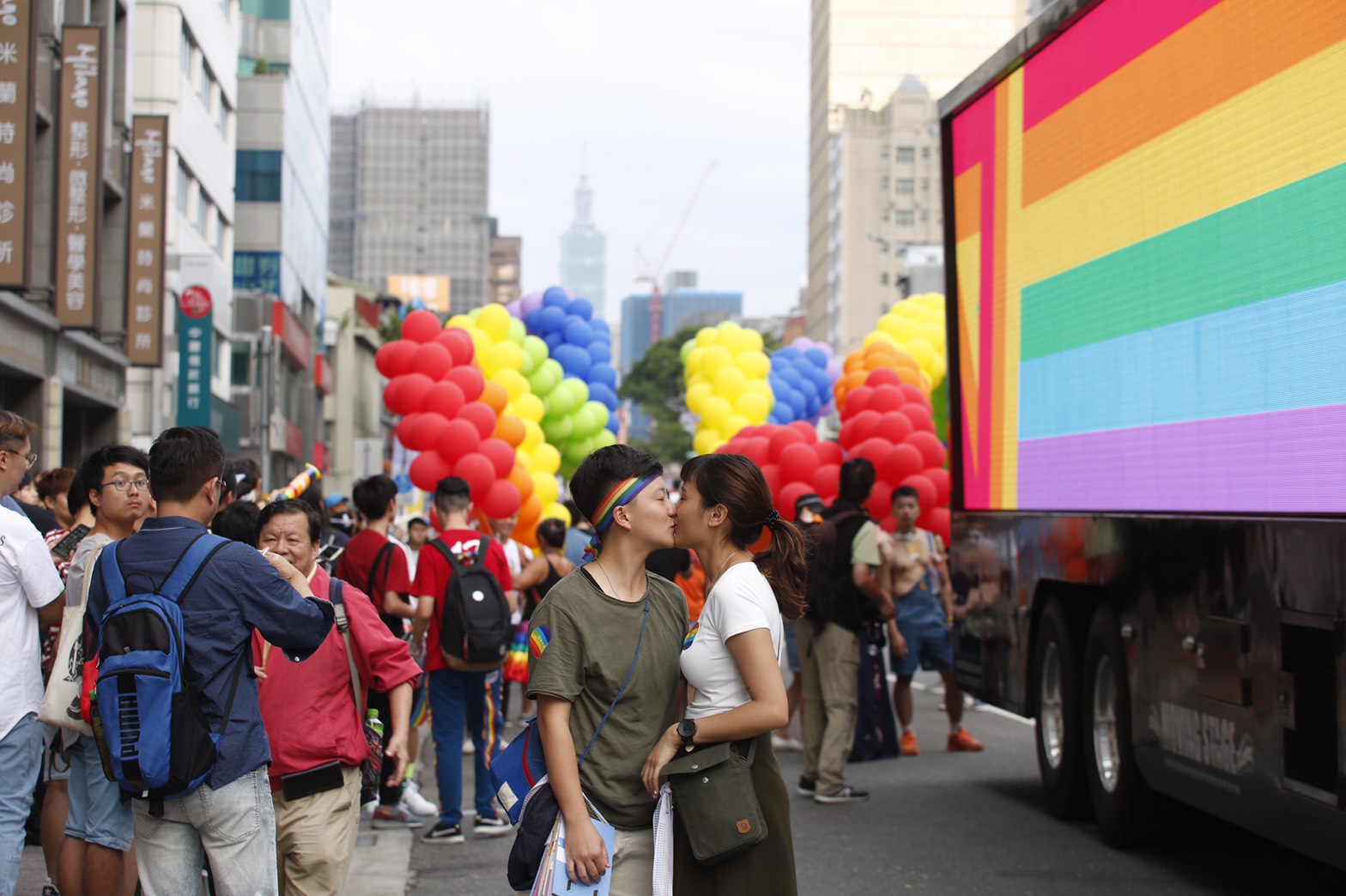 情侶在彩虹旗前接吻。