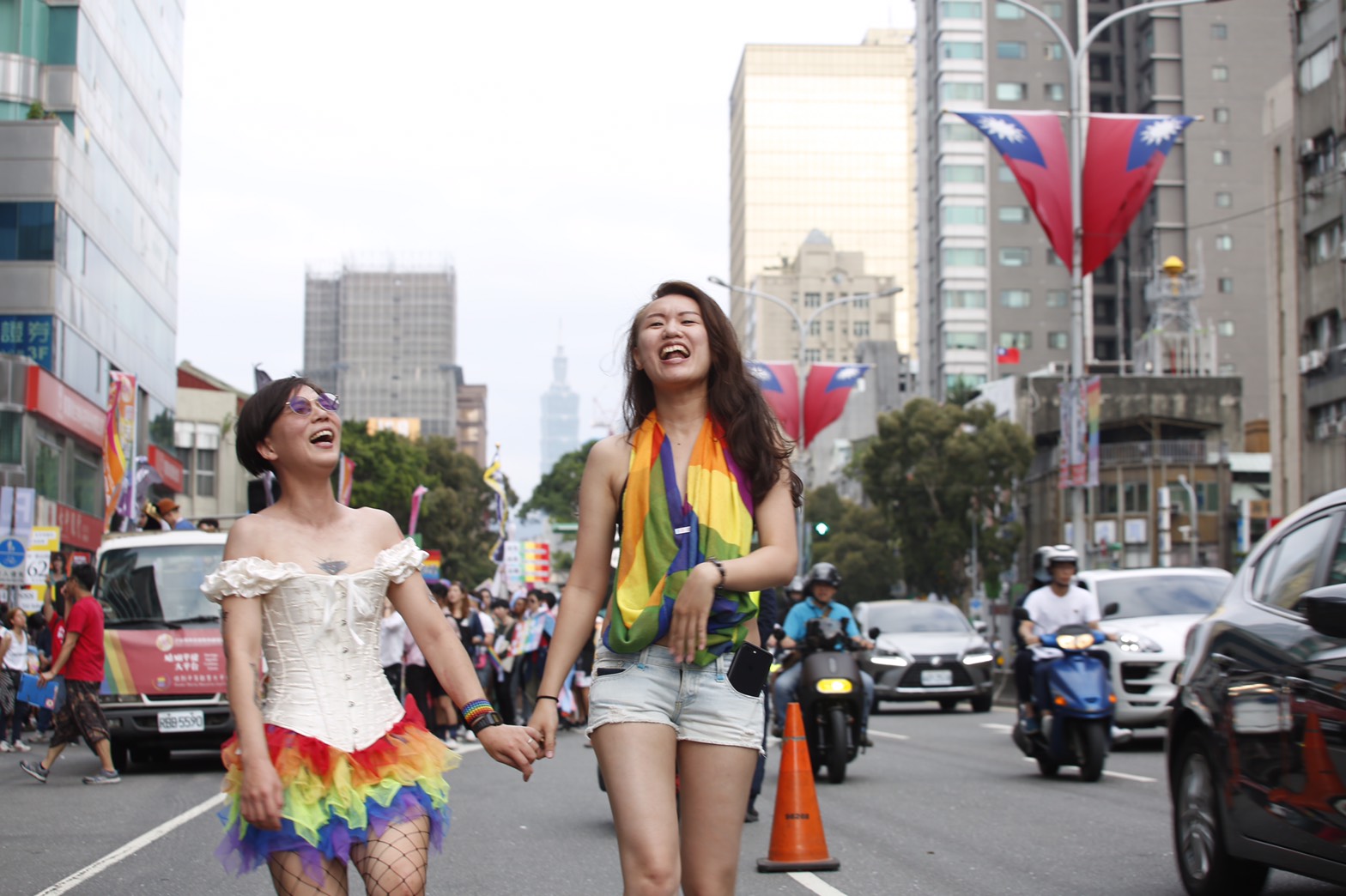 有女同志情侶在大街上大方牽手、自在開心笑著。