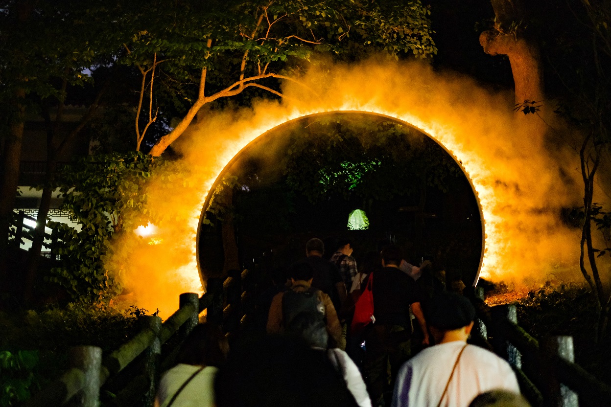 飄渺氣質的《Arc Zero》，夜裡看也像火圈，框入後方的客家人紀念碑。