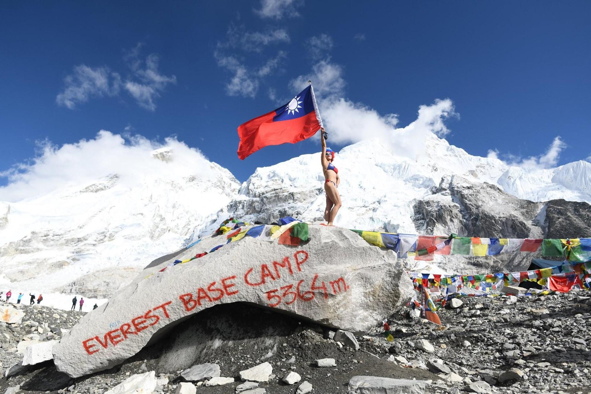 台灣女登山客在聖母峰換裝國旗比基尼,在基地營揮舞國旗拍照留念。(翻攝自攝界 敏平方粉絲專頁)