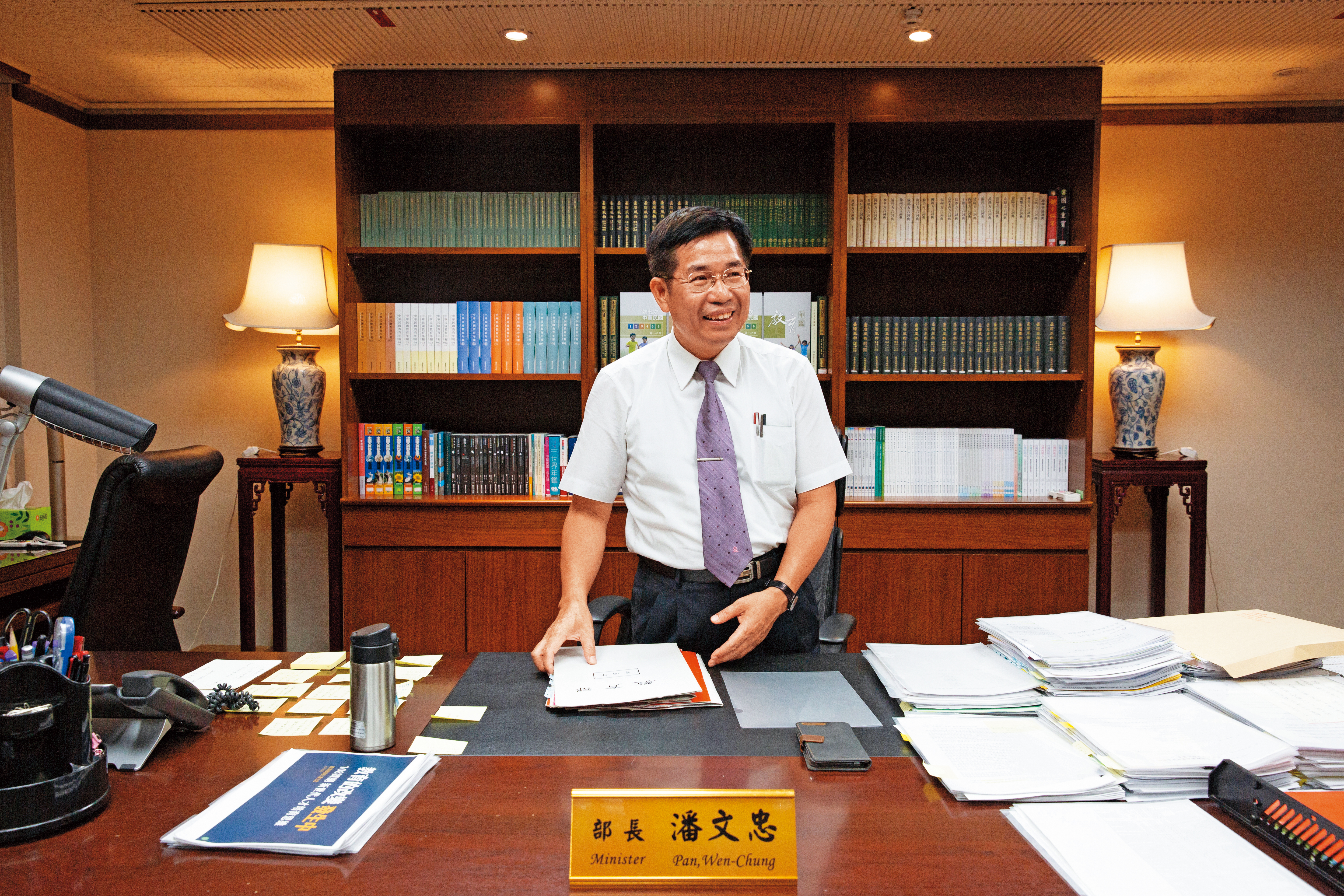 我們約在部長室採訪，採訪前一刻，潘文忠還在批閱公文。辦公桌的文件整齊分類堆放，右手邊的便利貼用來提醒自己重要事項。