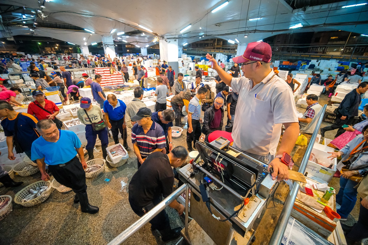 這晚漁獲豐收，拍賣員上台，下頭買家各自選擇魚貨。