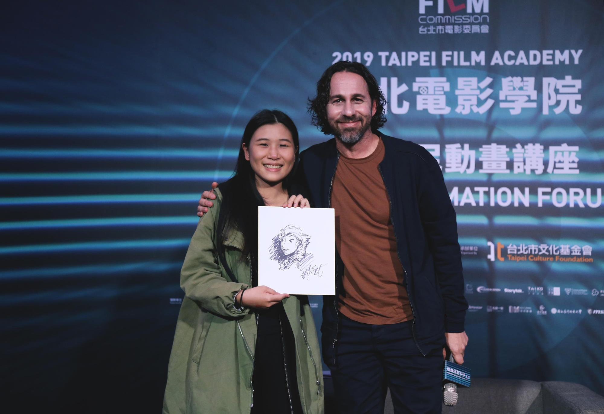 馬克史密斯(右)以親手繪製的艾莎女王圖像,送給講座上提問的幸運粉絲。(台北市影委會提供)