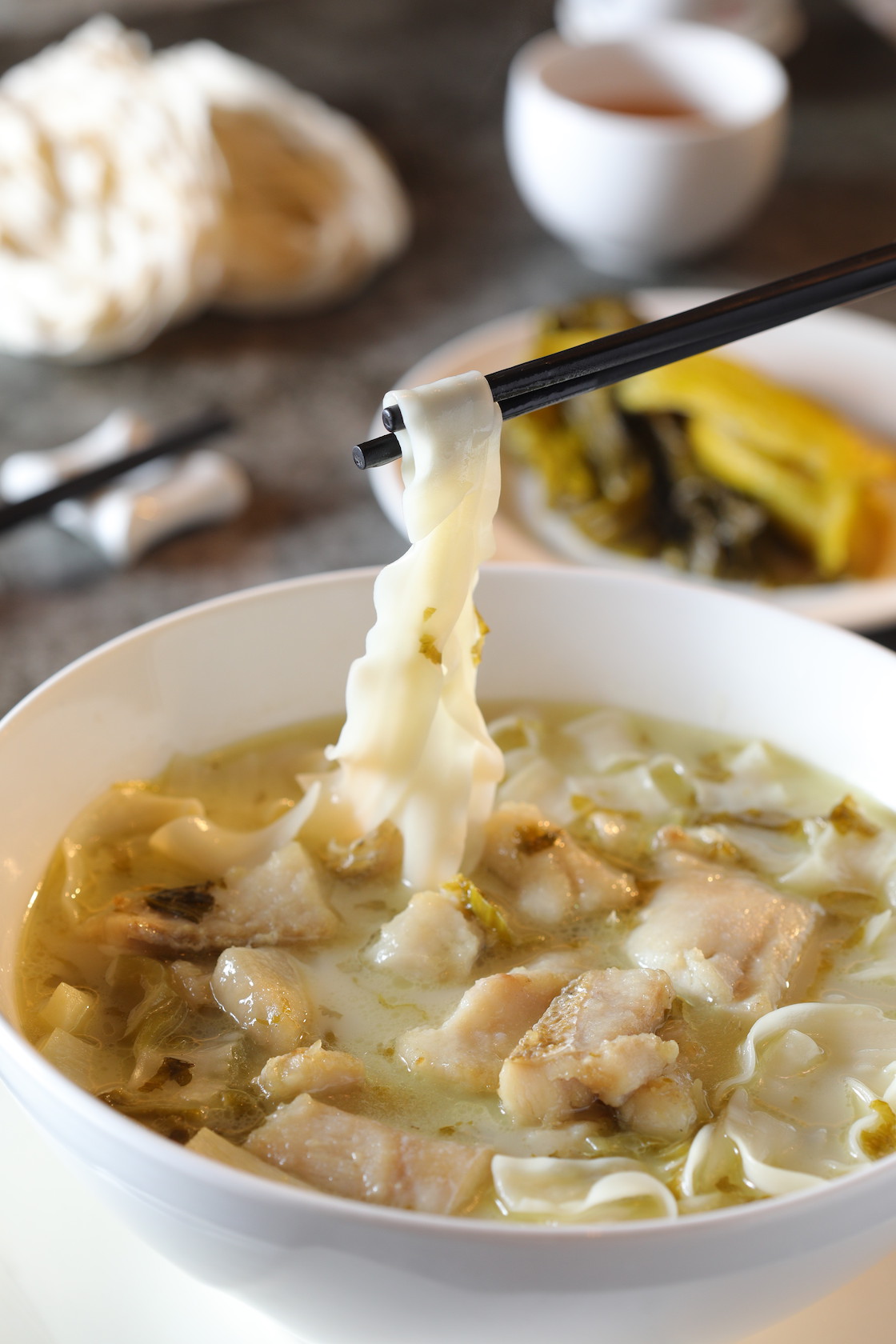 「鹹菜鮮魚湯寬麵」用的是與黃魚同屬石首魚類的火口魚，酸菜奶湯的鮮美鑽進緊實的魚肉裡。（320元／份）